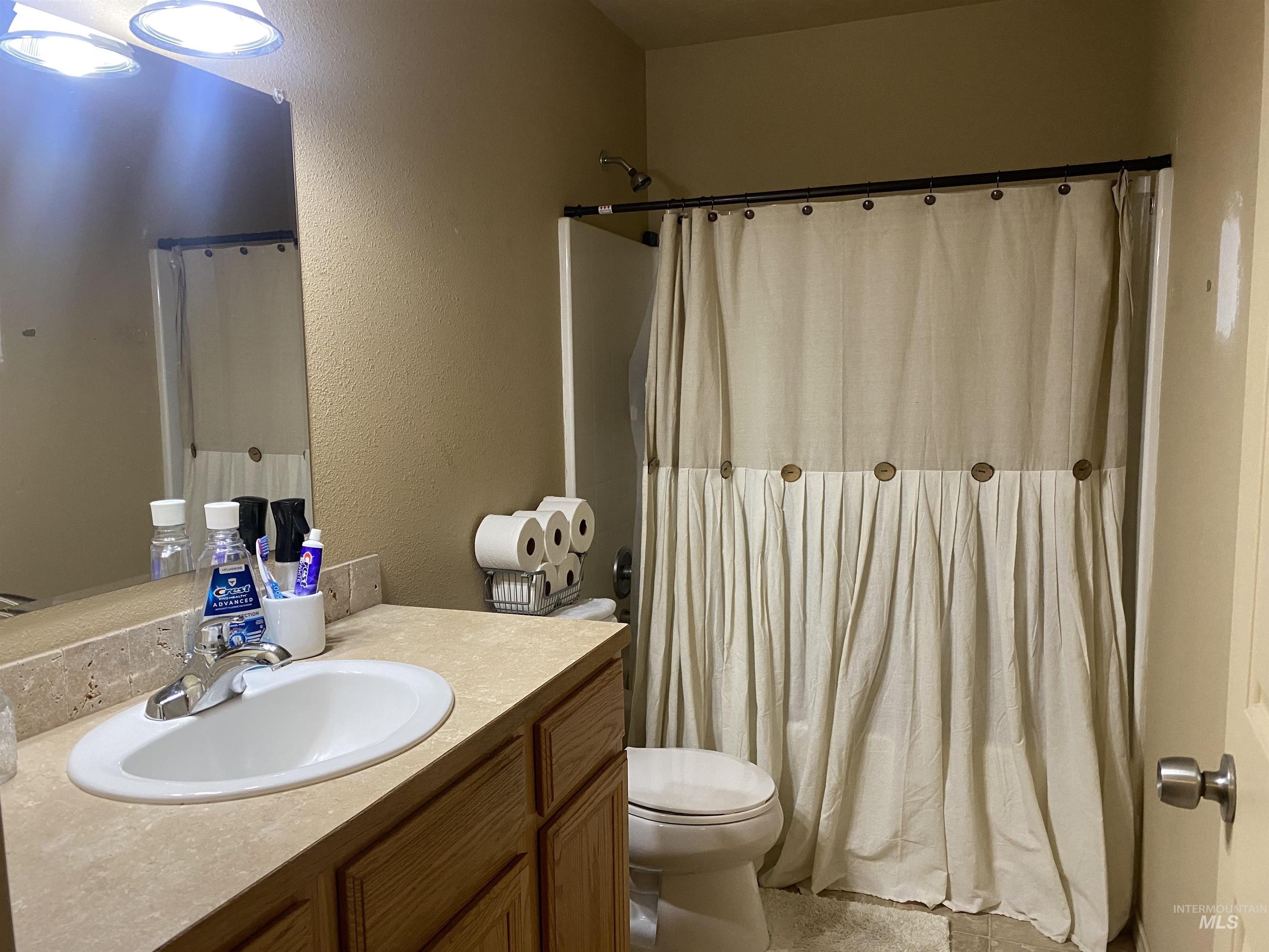 Full bathroom with vanity, a textured wall, and curtained shower