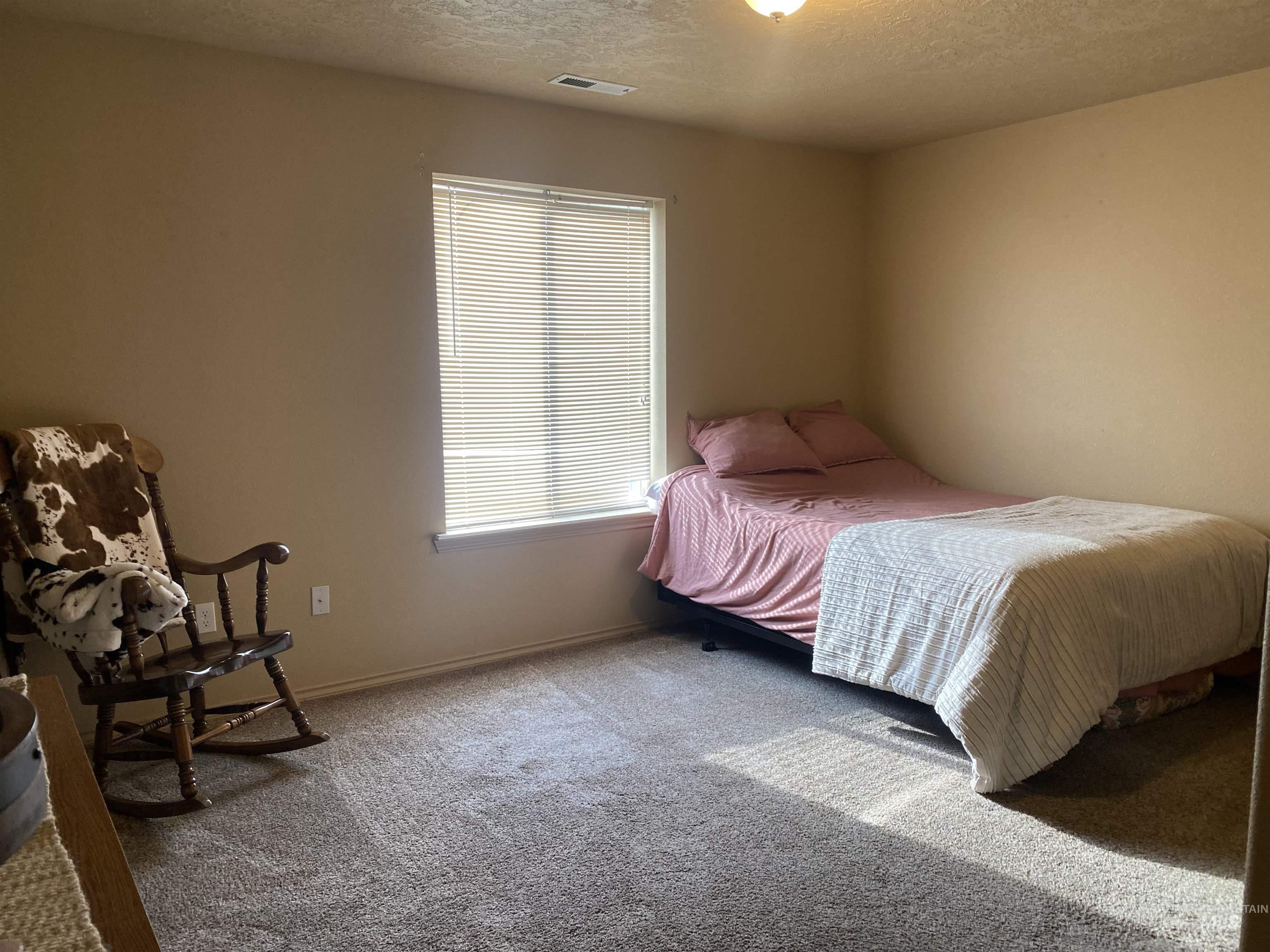 Bedroom with a textured ceiling and carpet floors