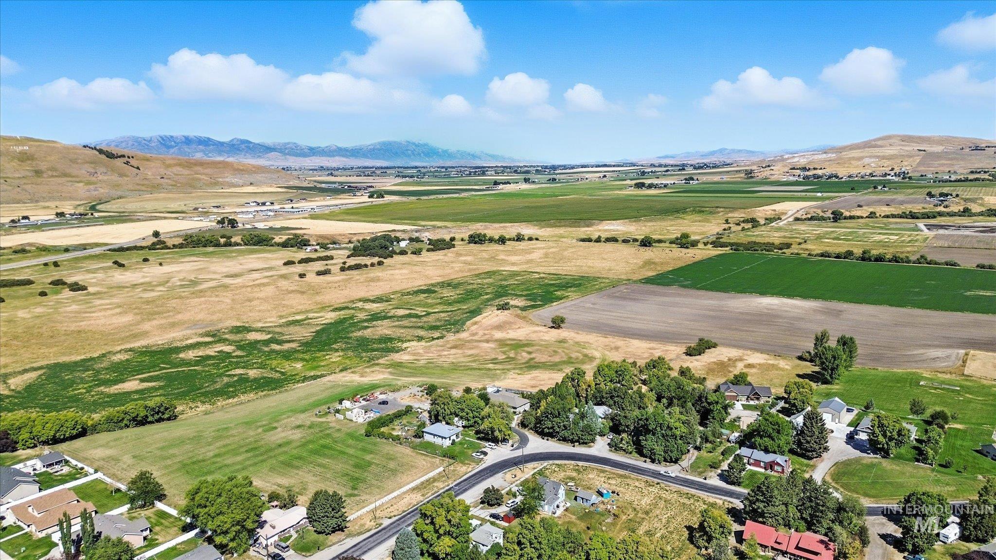 Aerial view of property's location with a mountain backdrop, rural landscape, and large plots for crops