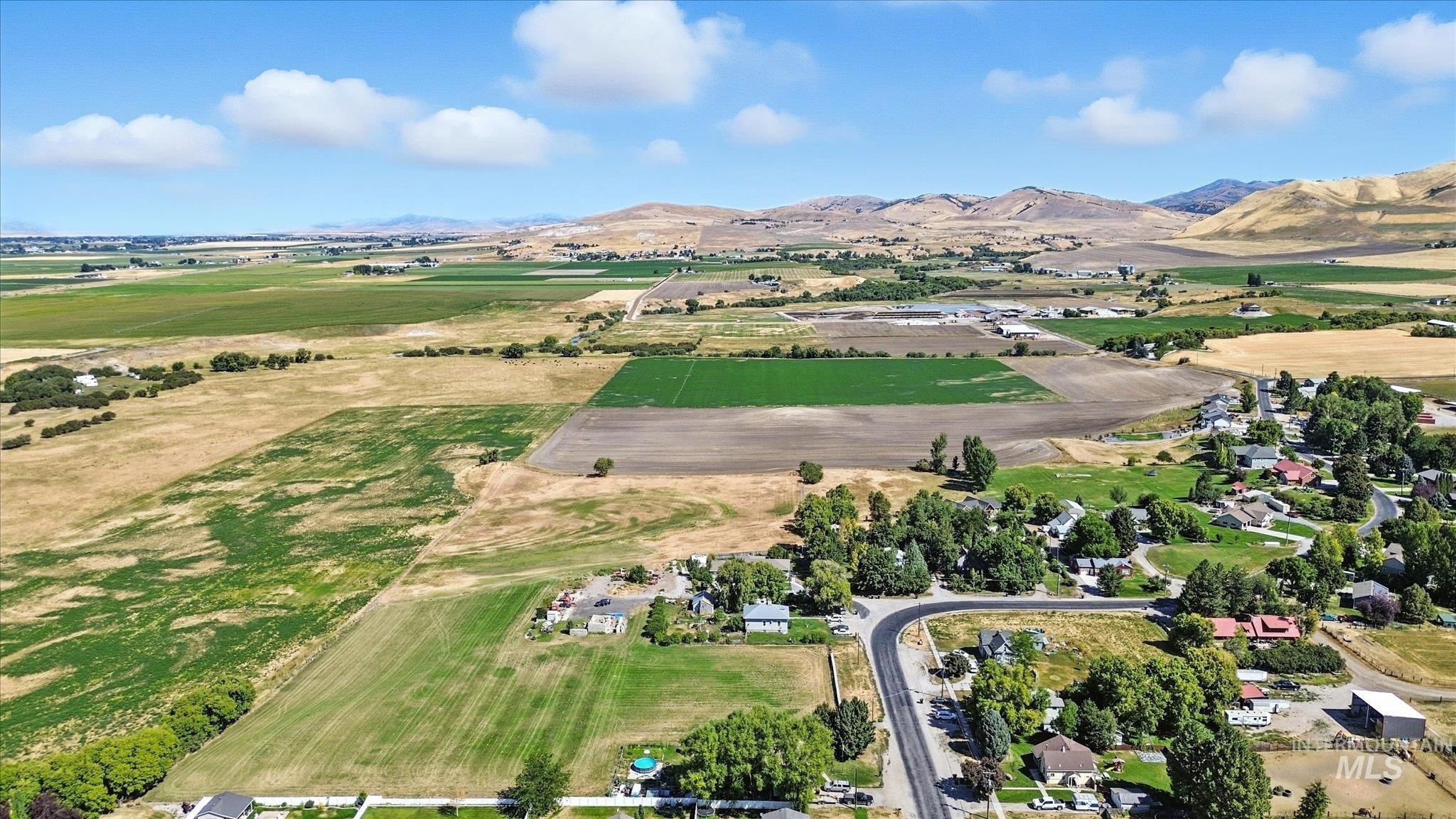 Aerial view of property's location with rural landscape, a mountain backdrop, and rows of crops