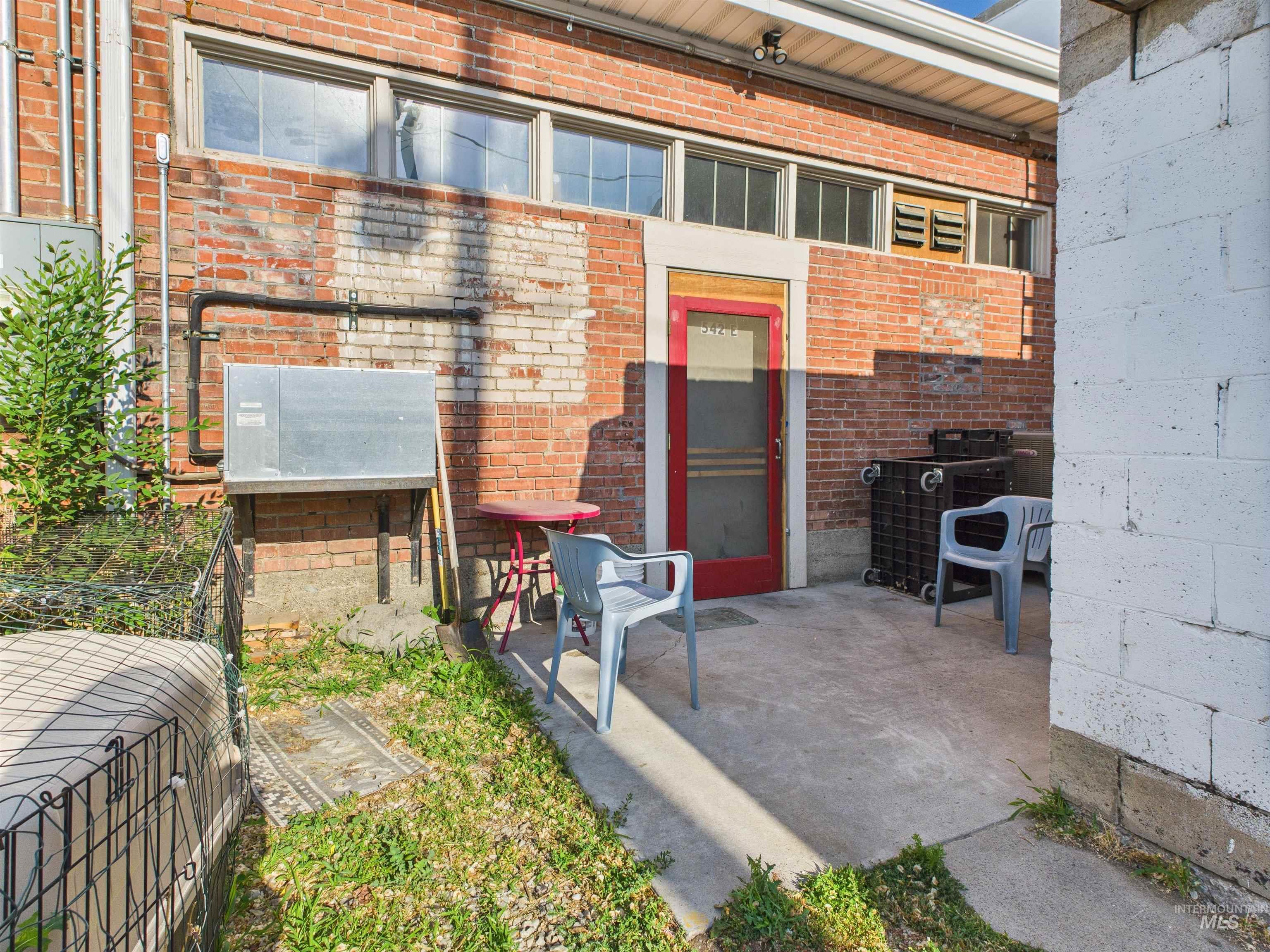 View of exterior entry featuring brick siding and a patio