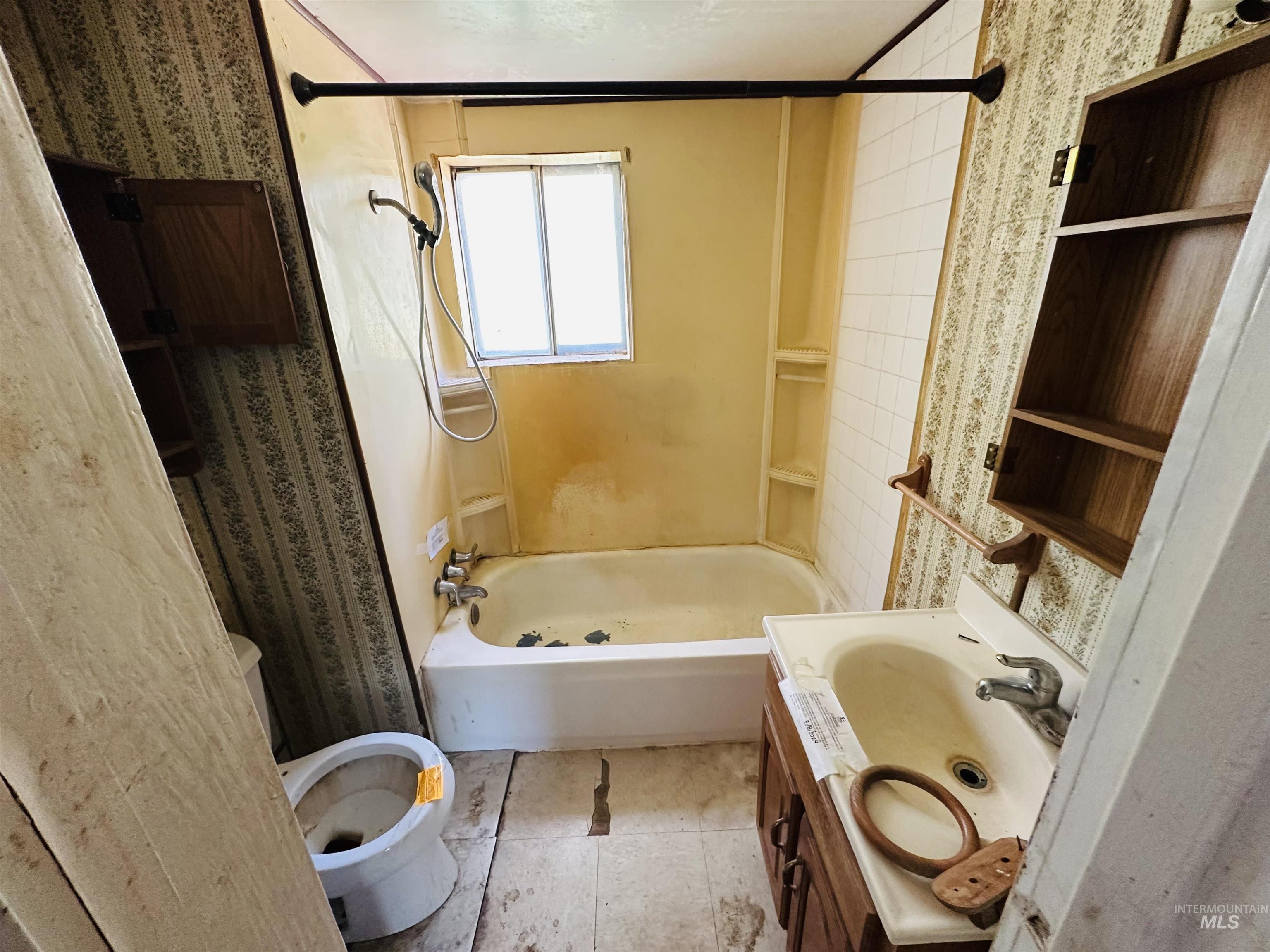 Full bathroom featuring vanity, shower / tub combination, and wallpapered walls