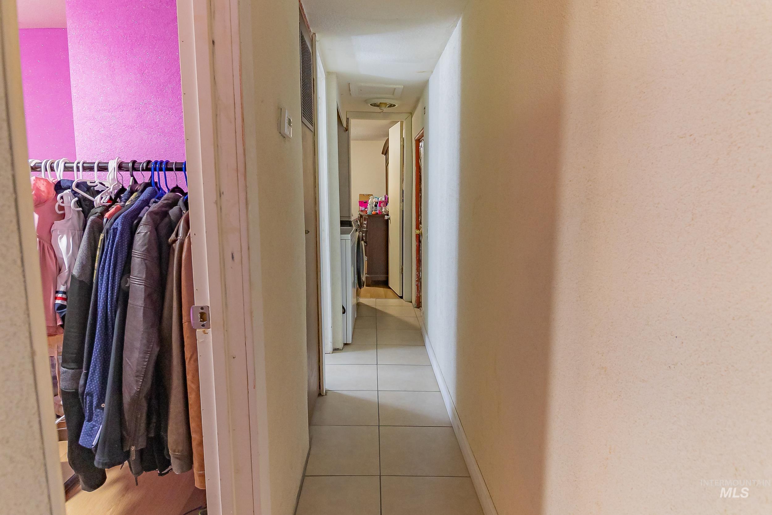 Corridor featuring light tile patterned flooring and attic access