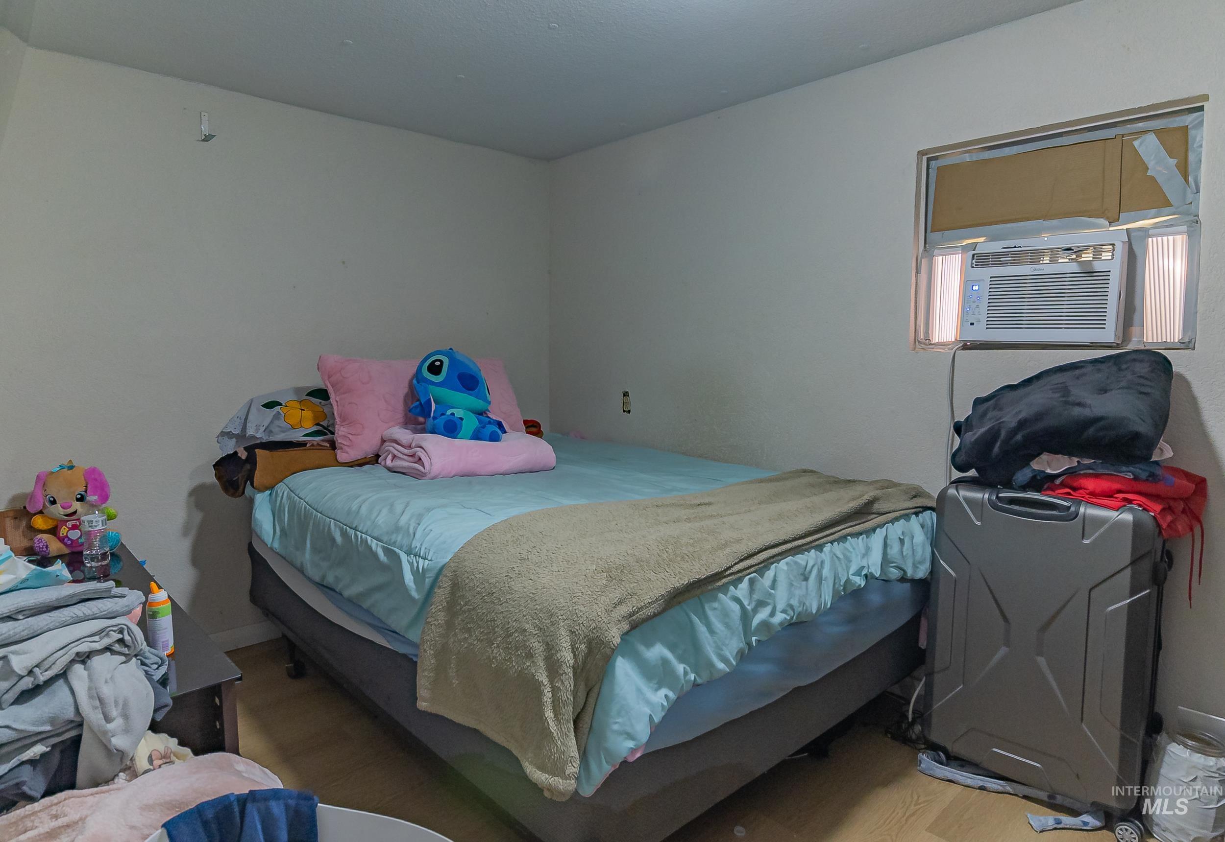 Bedroom with wood finished floors and cooling unit