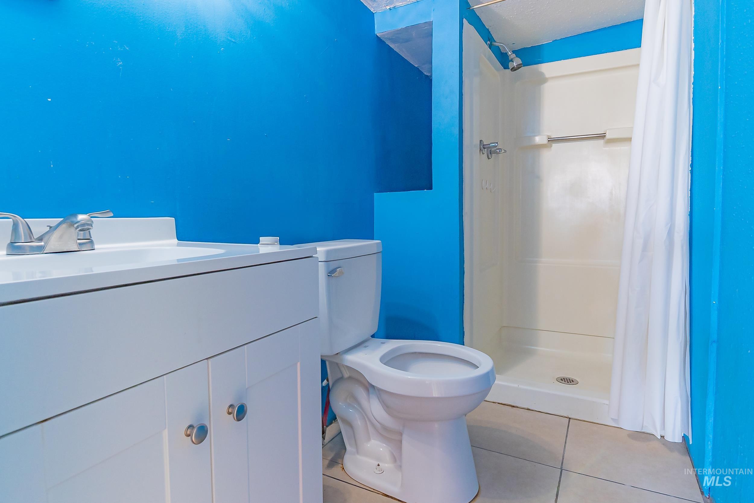Full bathroom featuring light tile patterned floors, vanity, and a shower stall