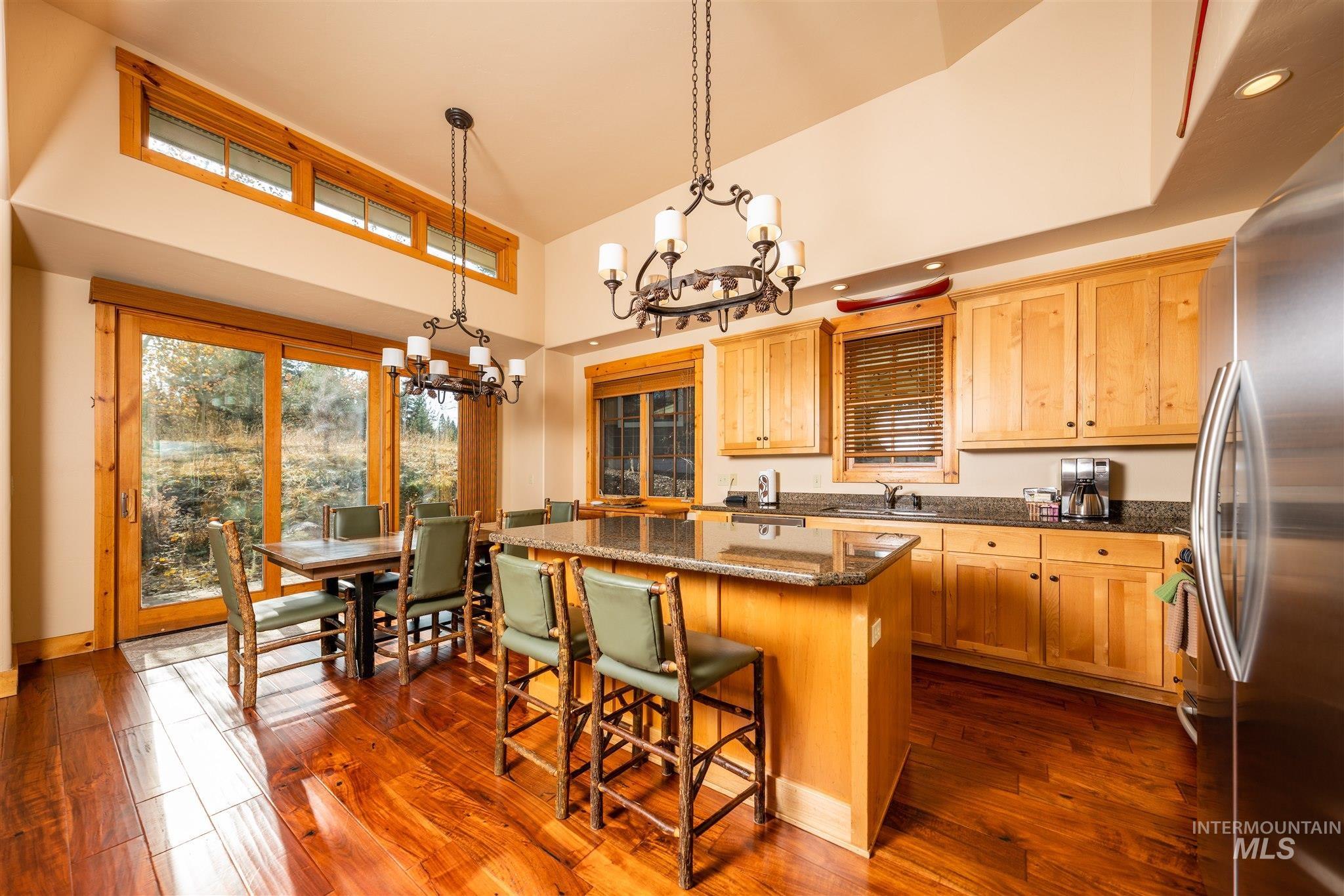 Kitchen featuring a chandelier, dark stone countertops, decorative light fixtures, freestanding refrigerator, and a center island