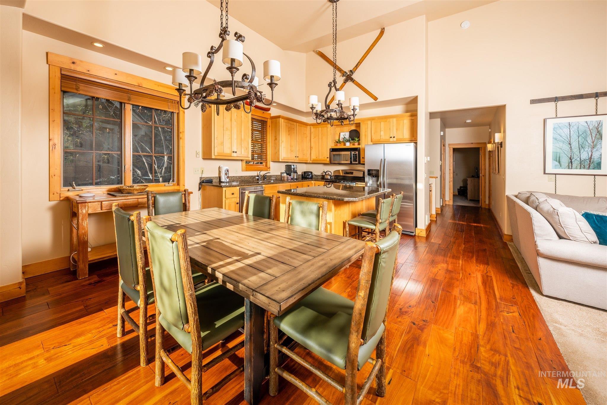 Dining area with a high ceiling, dark wood-style flooring, a chandelier, and recessed lighting