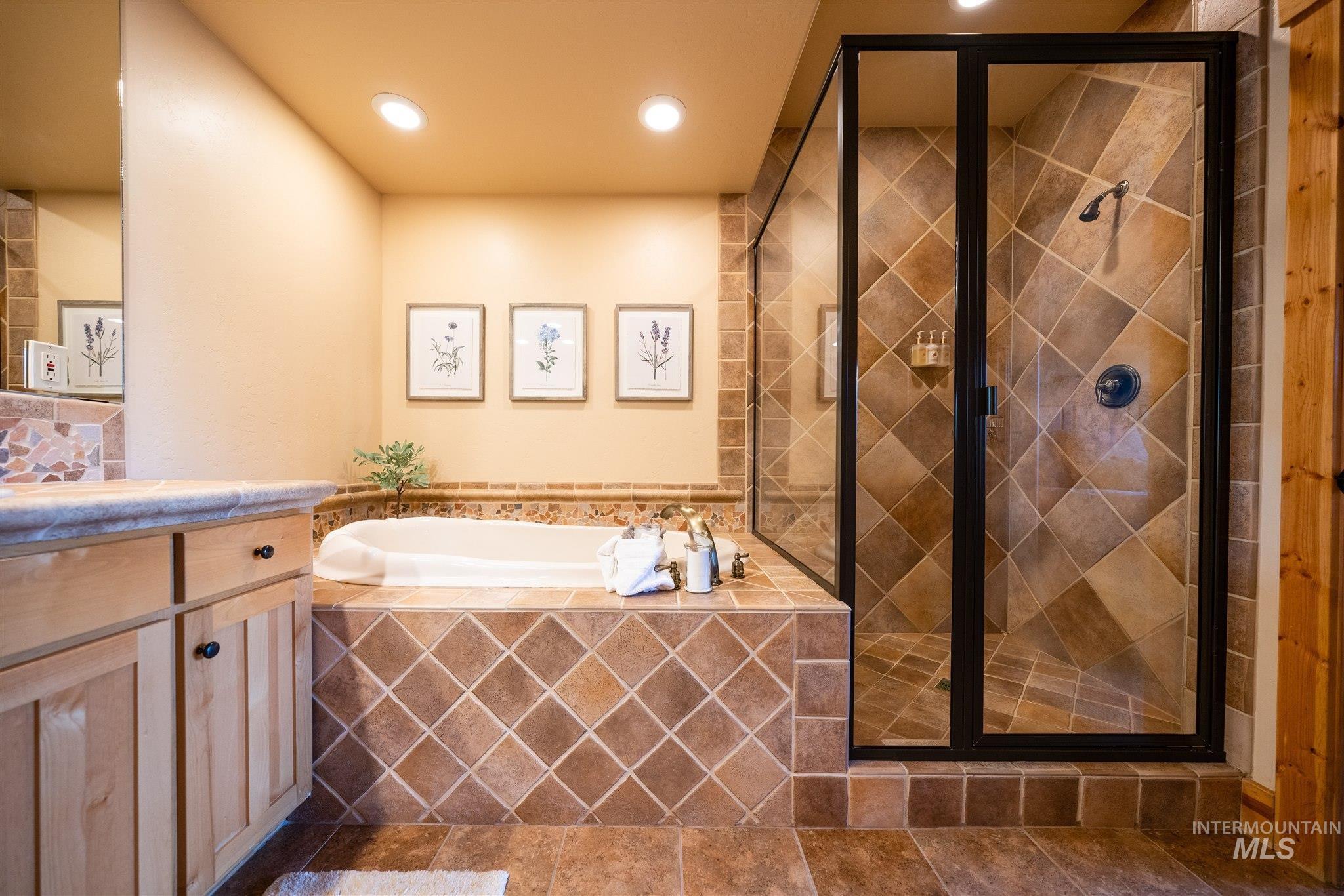 Full bath featuring vanity, a shower stall, a bath, recessed lighting, and dark tile patterned flooring