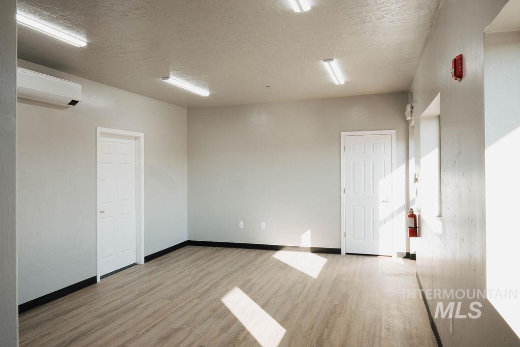 Unfurnished room featuring wood finished floors, a wall mounted air conditioner, and a textured ceiling
