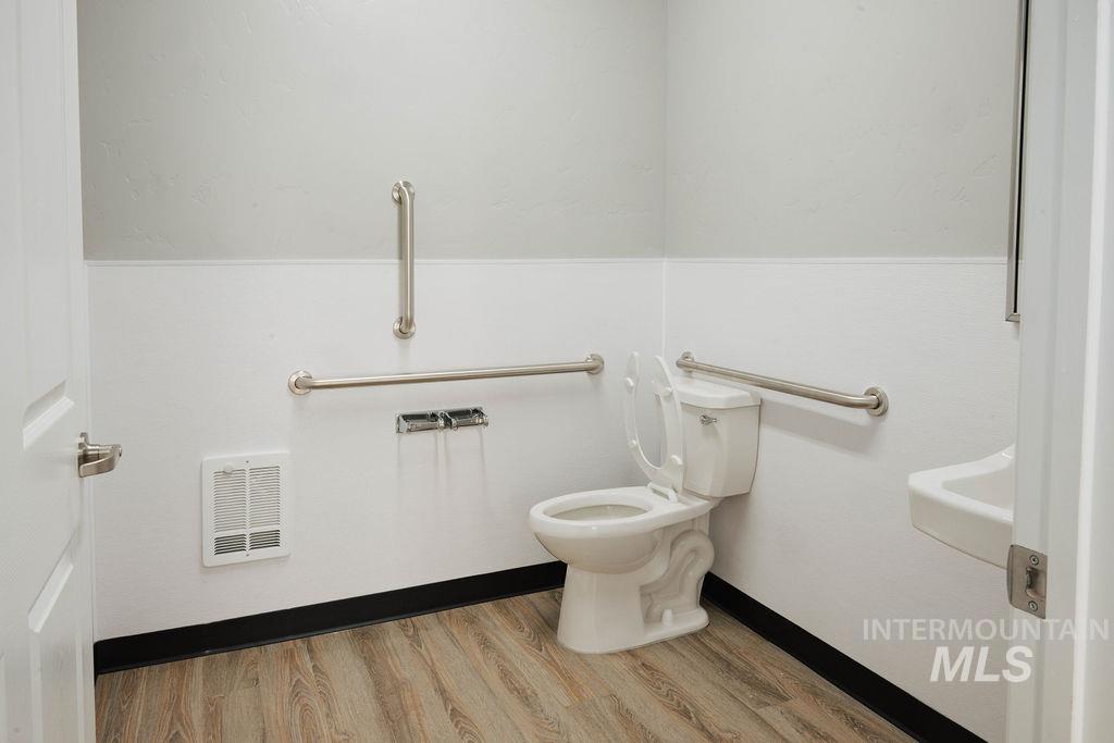 Half bath featuring toilet and wood finished floors