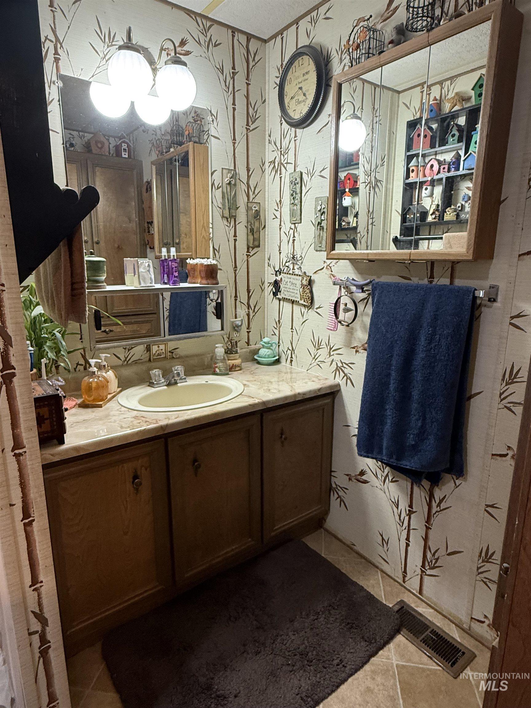 Bathroom featuring tile patterned flooring, wallpapered walls, and vanity