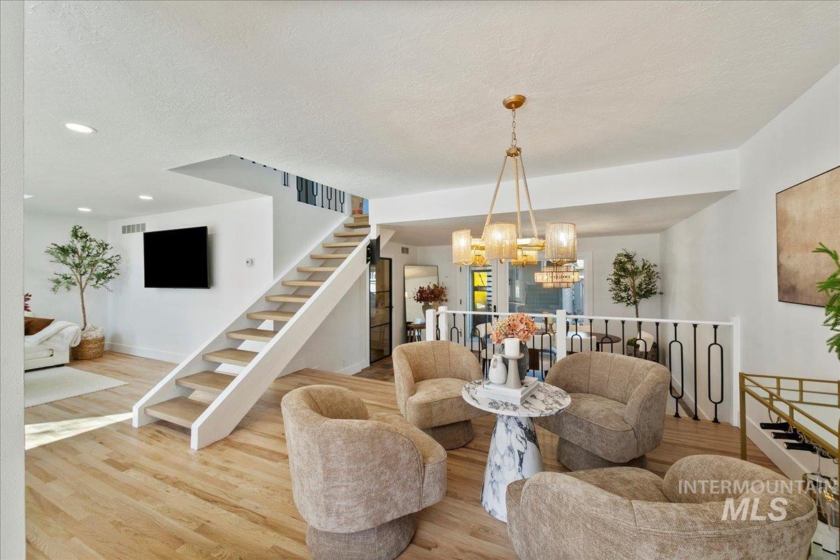 Dining space featuring stairway, a textured ceiling, wood finished floors, a chandelier, and recessed lighting