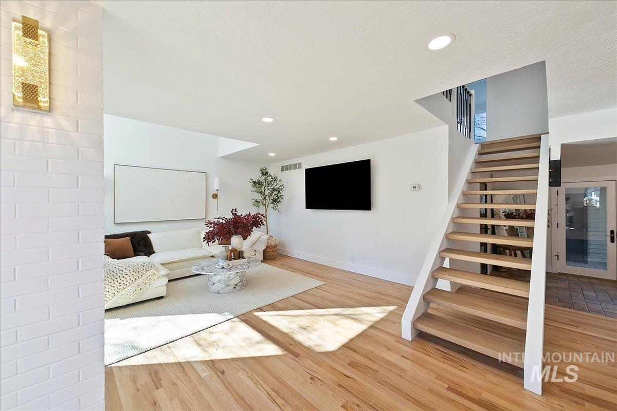 Living area featuring recessed lighting, light wood-style flooring, and stairs