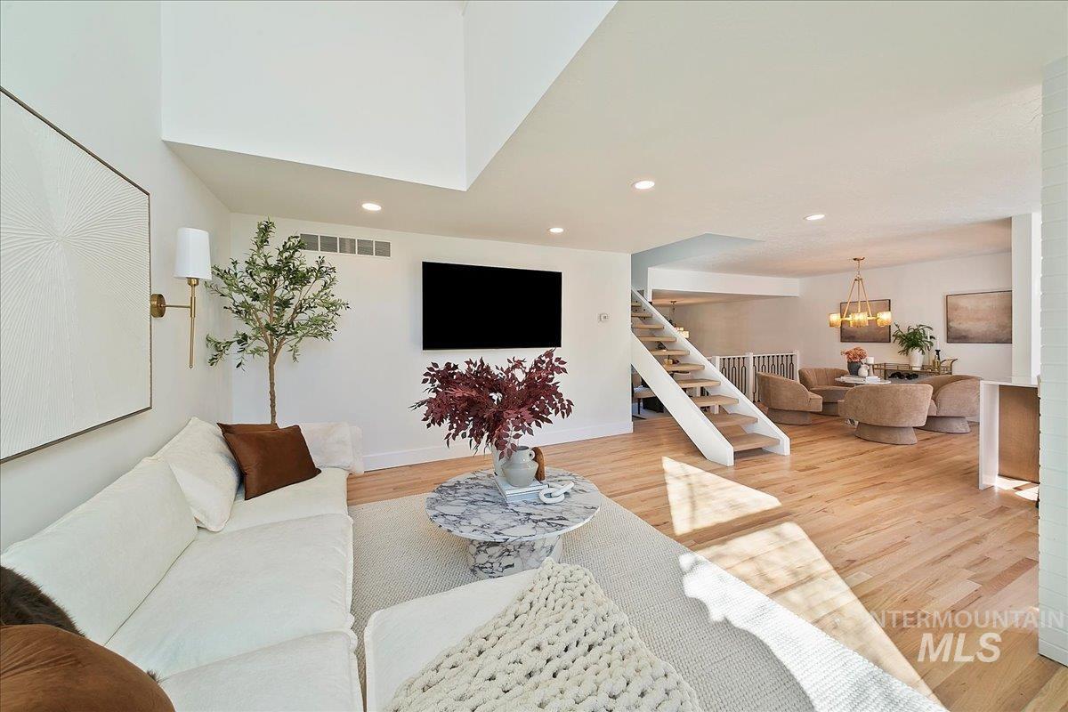 Living area with stairs, wood finished floors, recessed lighting, and a chandelier