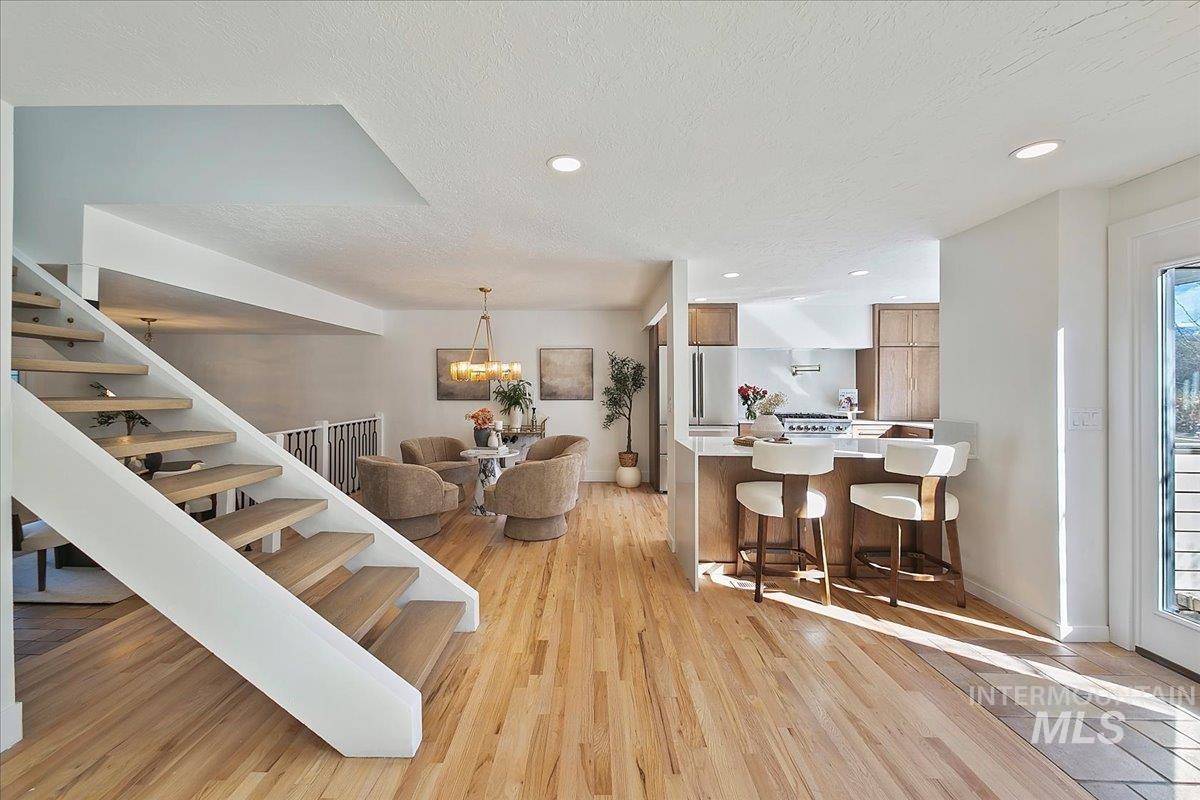 Dining room featuring stairway, light wood-style floors, a textured ceiling, recessed lighting, and a chandelier