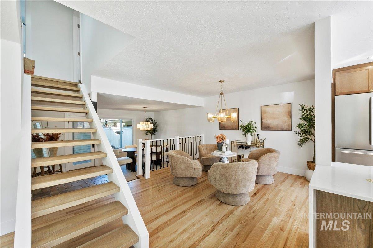 Dining room featuring stairs, a textured ceiling, light wood-type flooring, and a chandelier