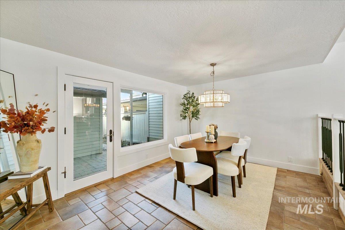 Dining room with a textured ceiling, a chandelier, and light stone finish flooring