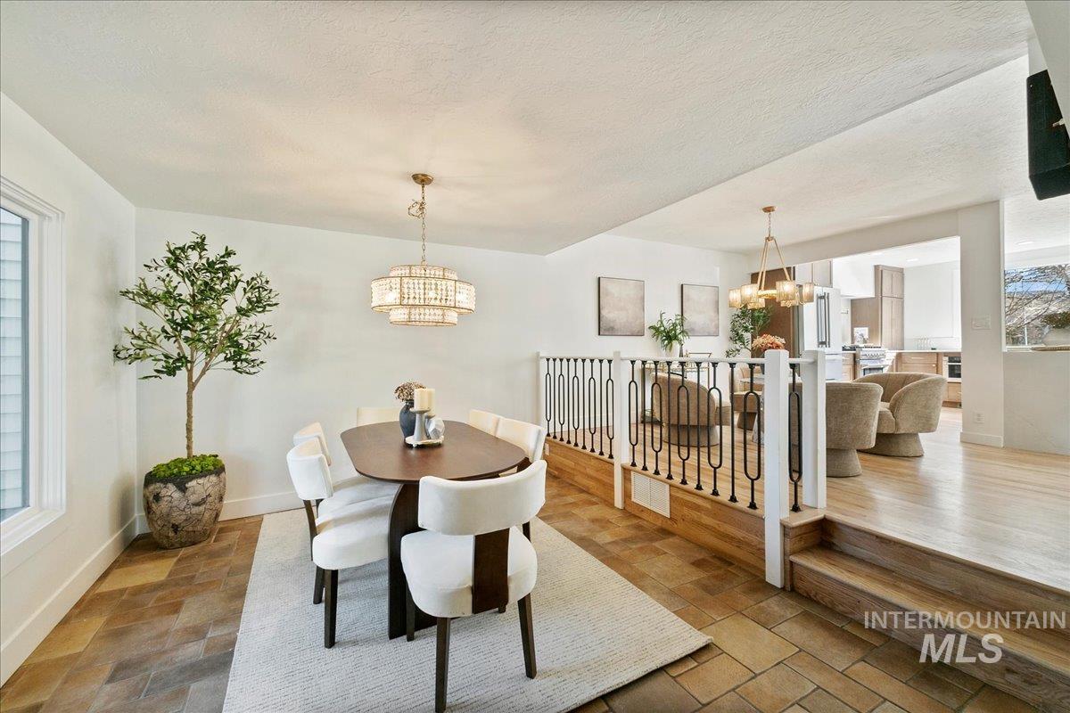 Dining area featuring a chandelier, a textured ceiling, and stone finish flooring