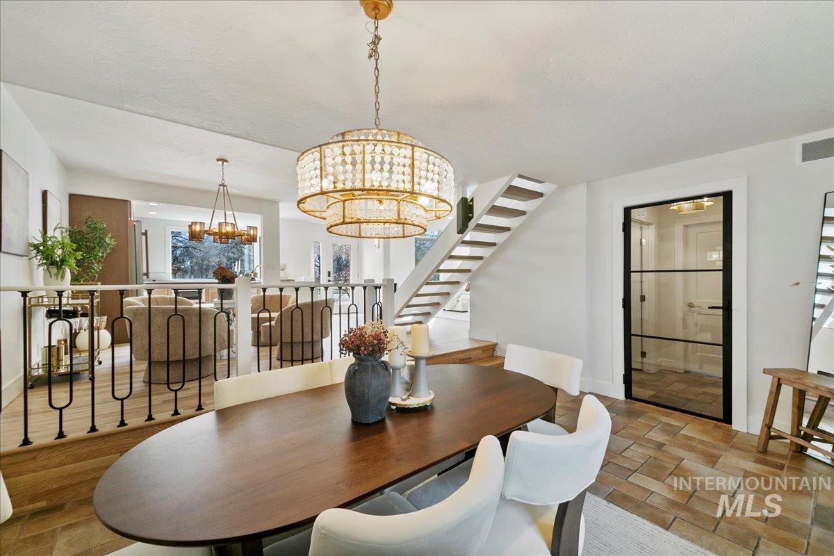 Dining space featuring stairs, a chandelier, and a textured ceiling