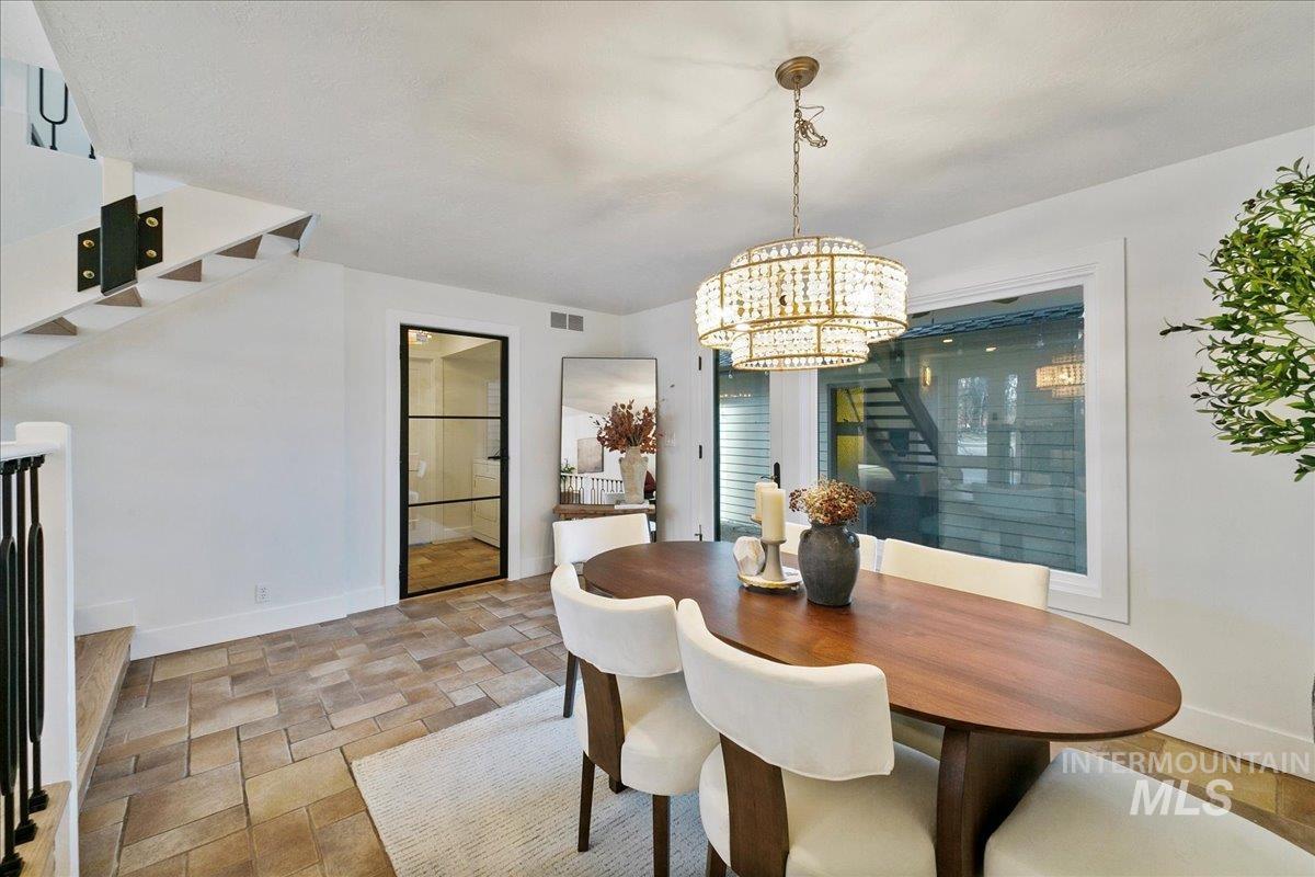 Dining space with stairs, light stone finish floors, and a chandelier