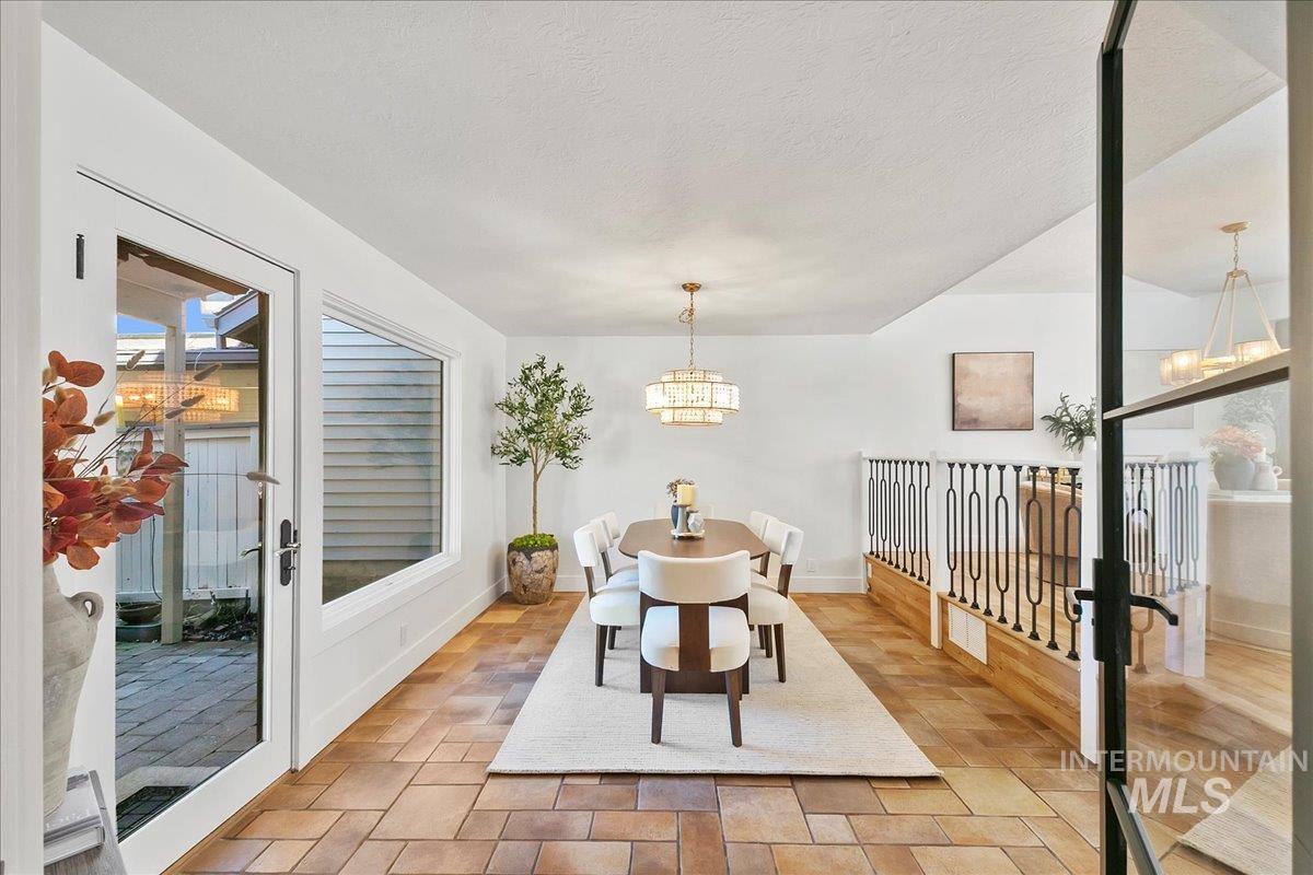 Dining room with a chandelier, healthy amount of natural light, a textured ceiling, and light tile patterned floors