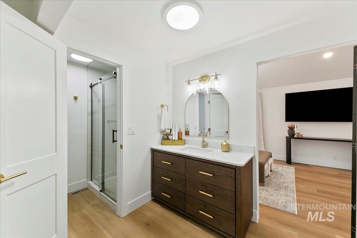 Bathroom featuring vanity, light wood-style flooring, and a shower stall
