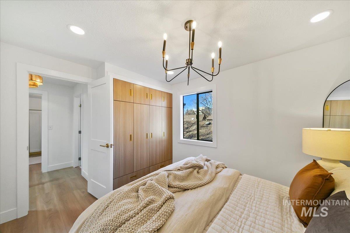 Bedroom with wood finished floors, a closet, recessed lighting, and a chandelier