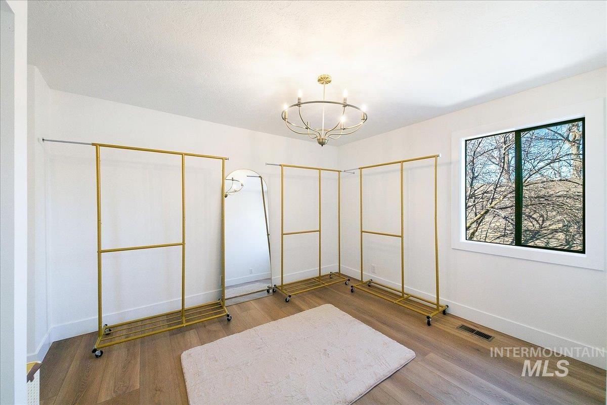 Unfurnished bedroom with wood finished floors, a chandelier, and multiple closets