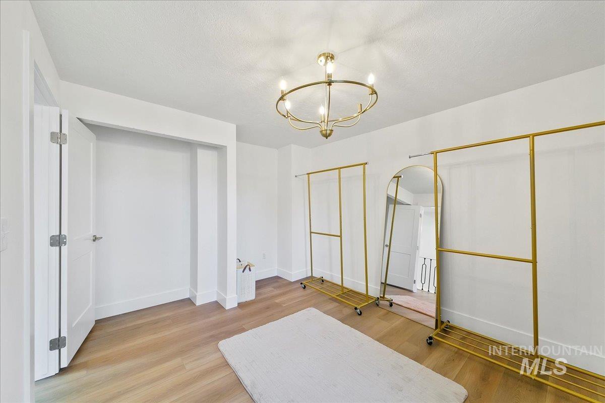 Unfurnished bedroom with two closets, light wood-type flooring, a chandelier, and a textured ceiling