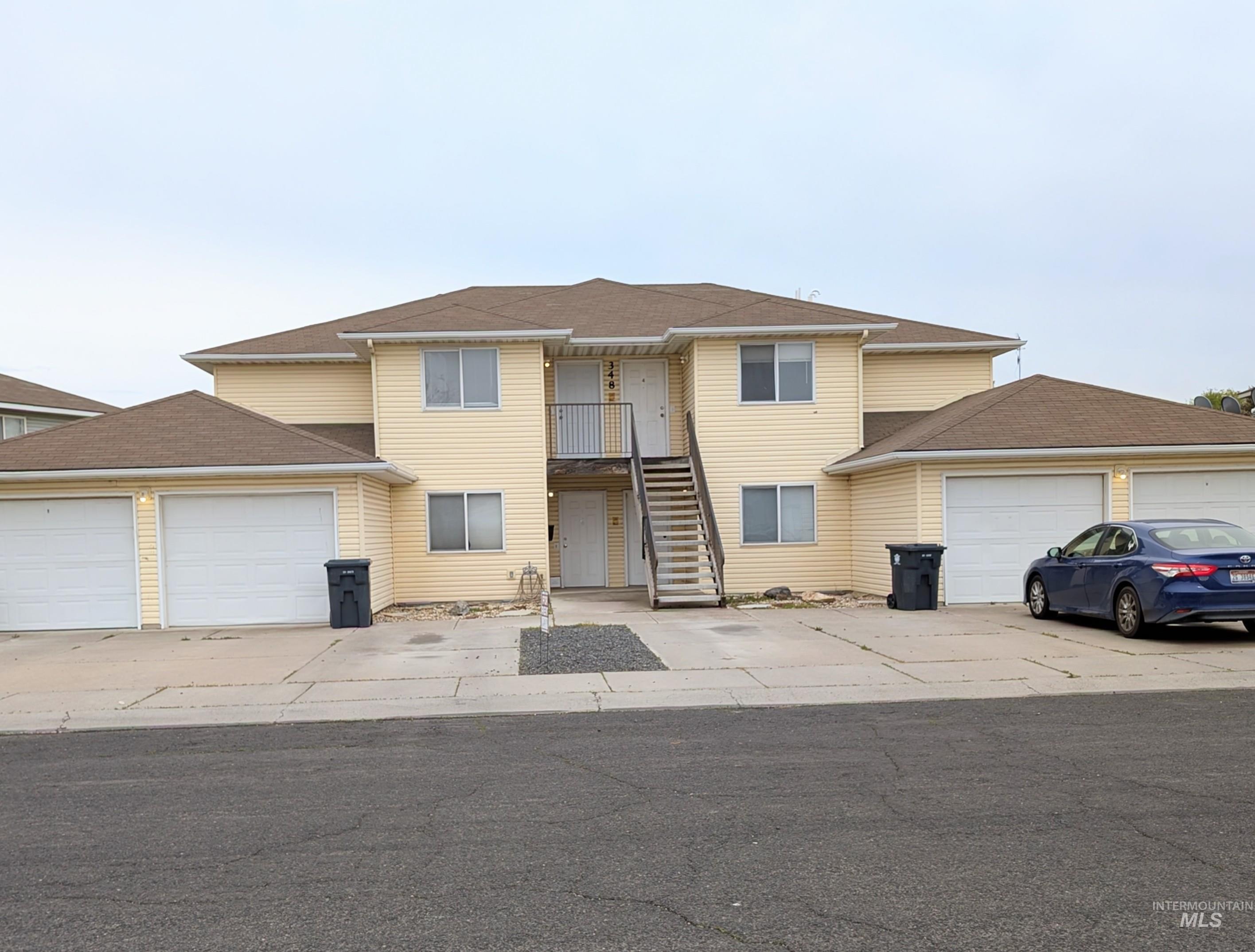 Traditional-style home with stairway, a balcony, concrete driveway, and an attached garage