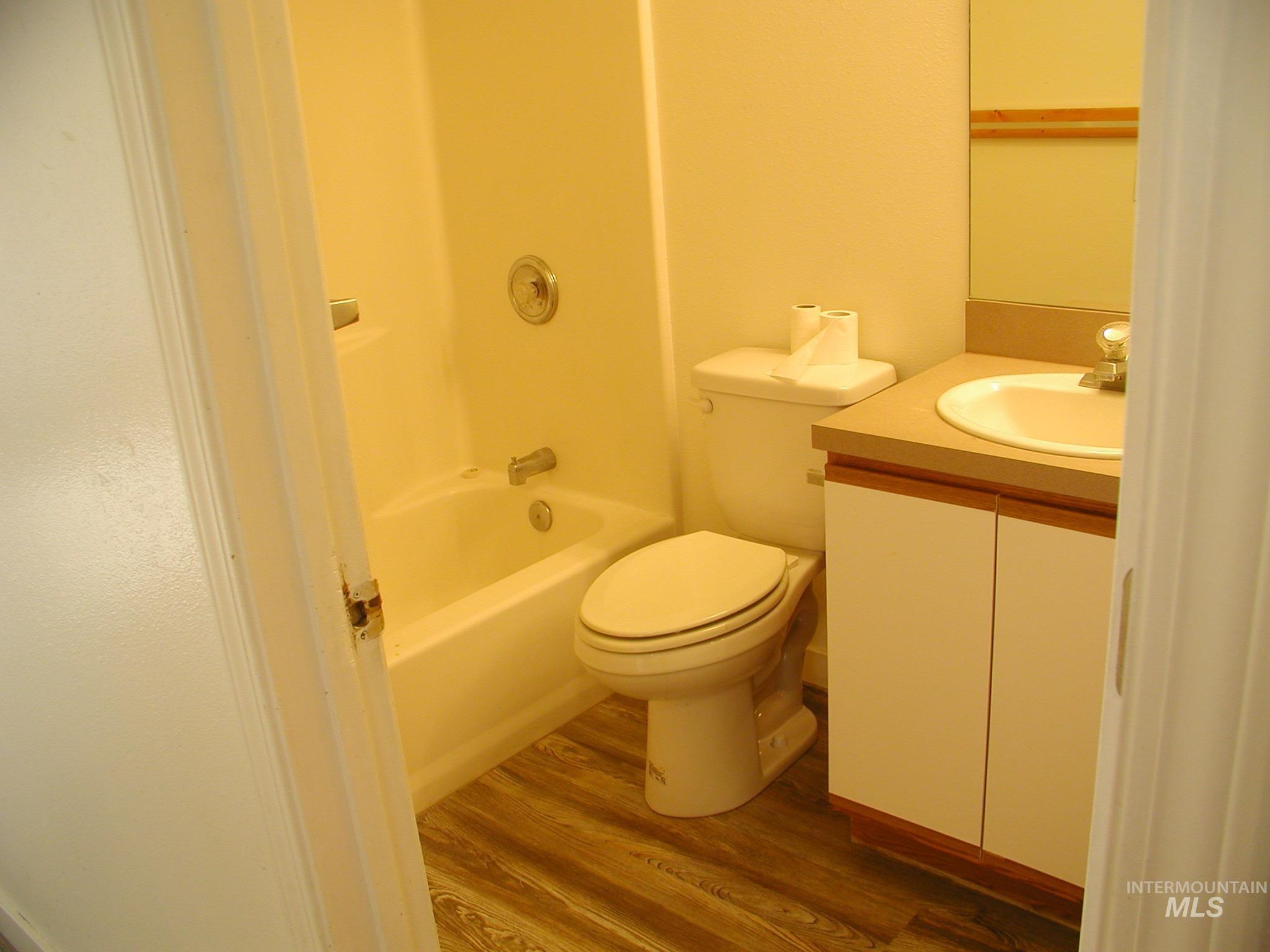 Bathroom with wood finished floors, vanity, and bathing tub / shower combination