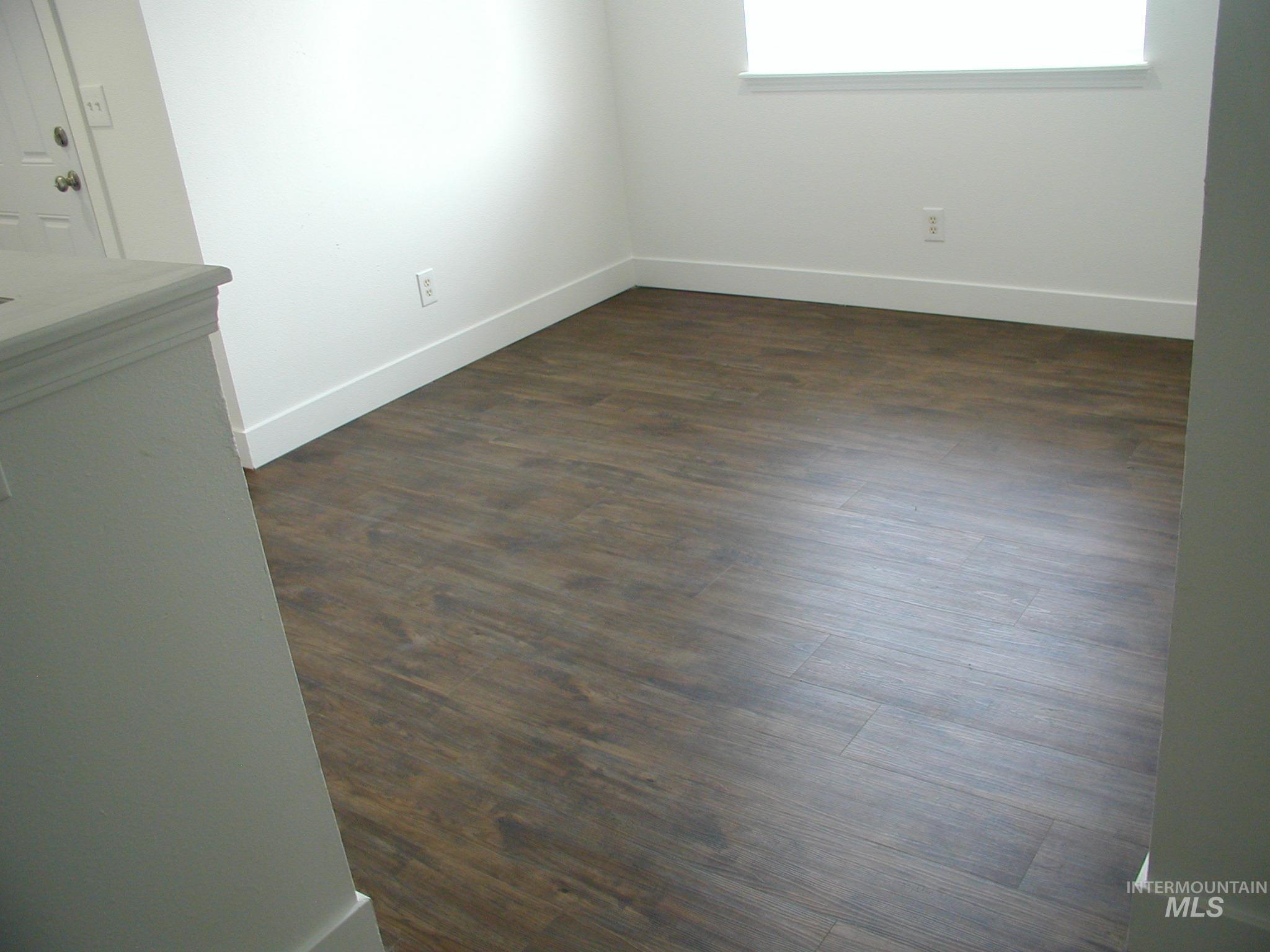 Empty room featuring baseboards and dark wood-type flooring