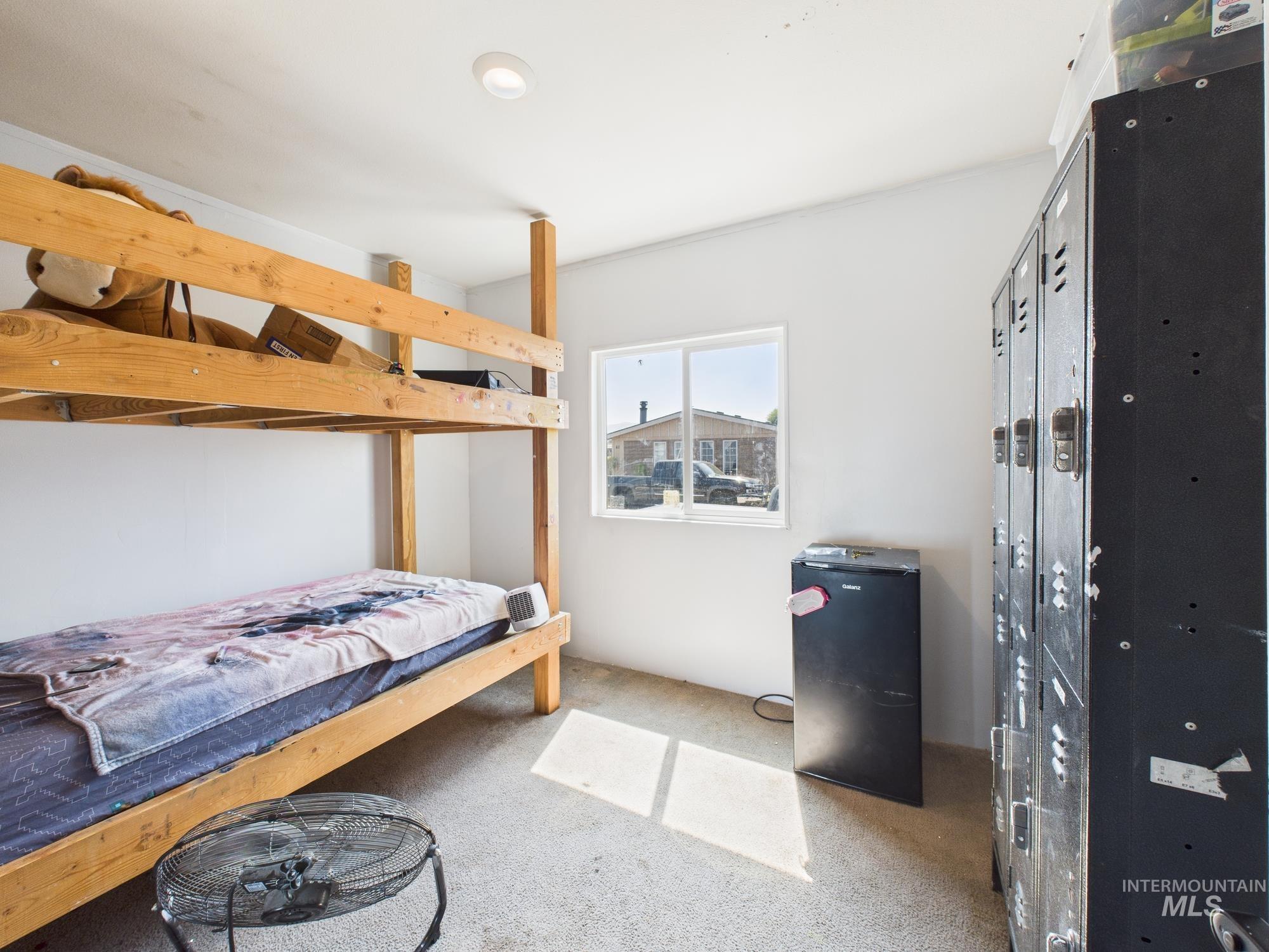 Bedroom featuring carpet floors and black refrigerator