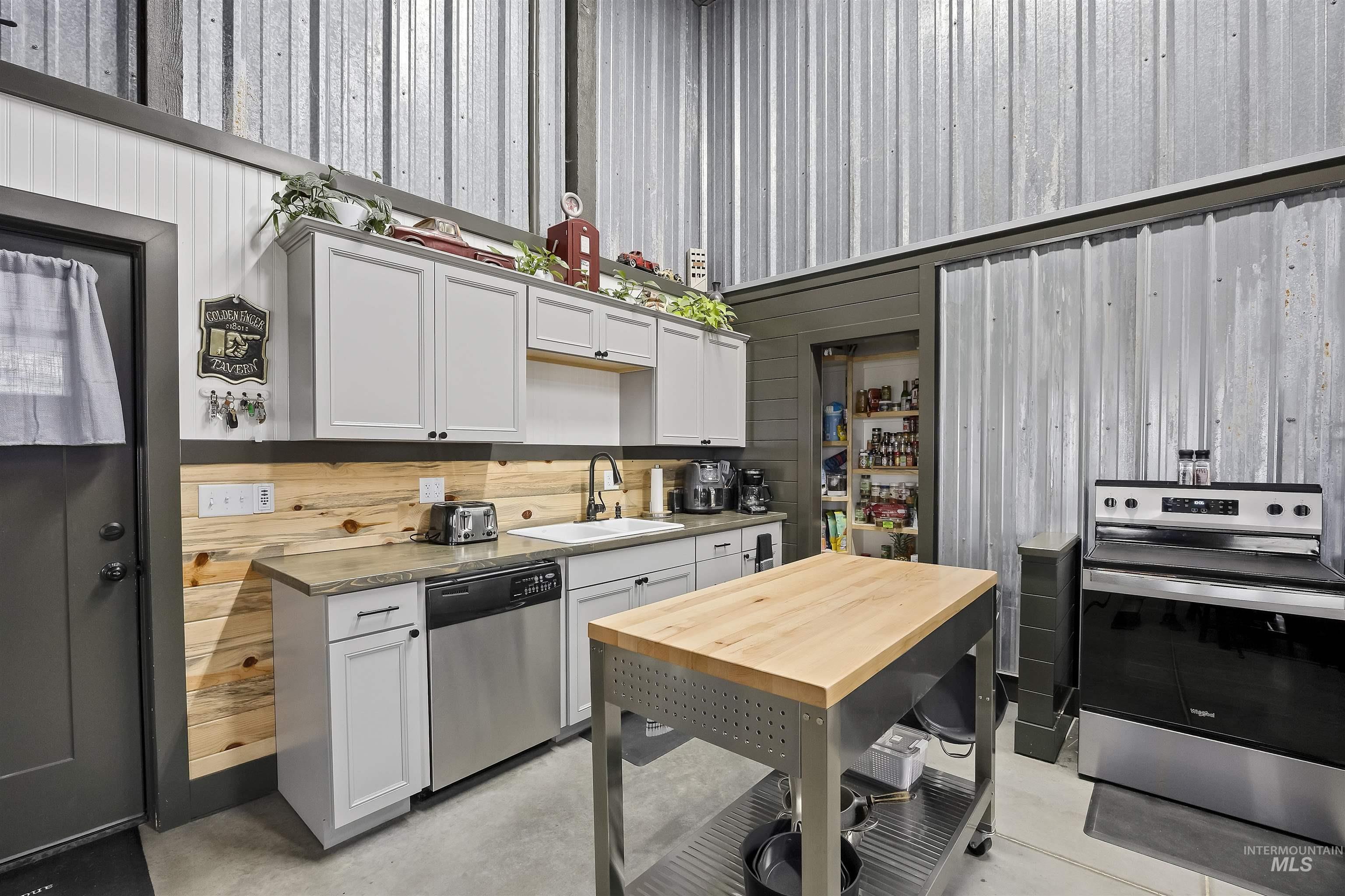 Kitchen with appliances with stainless steel finishes, finished concrete floors, and white cabinetry