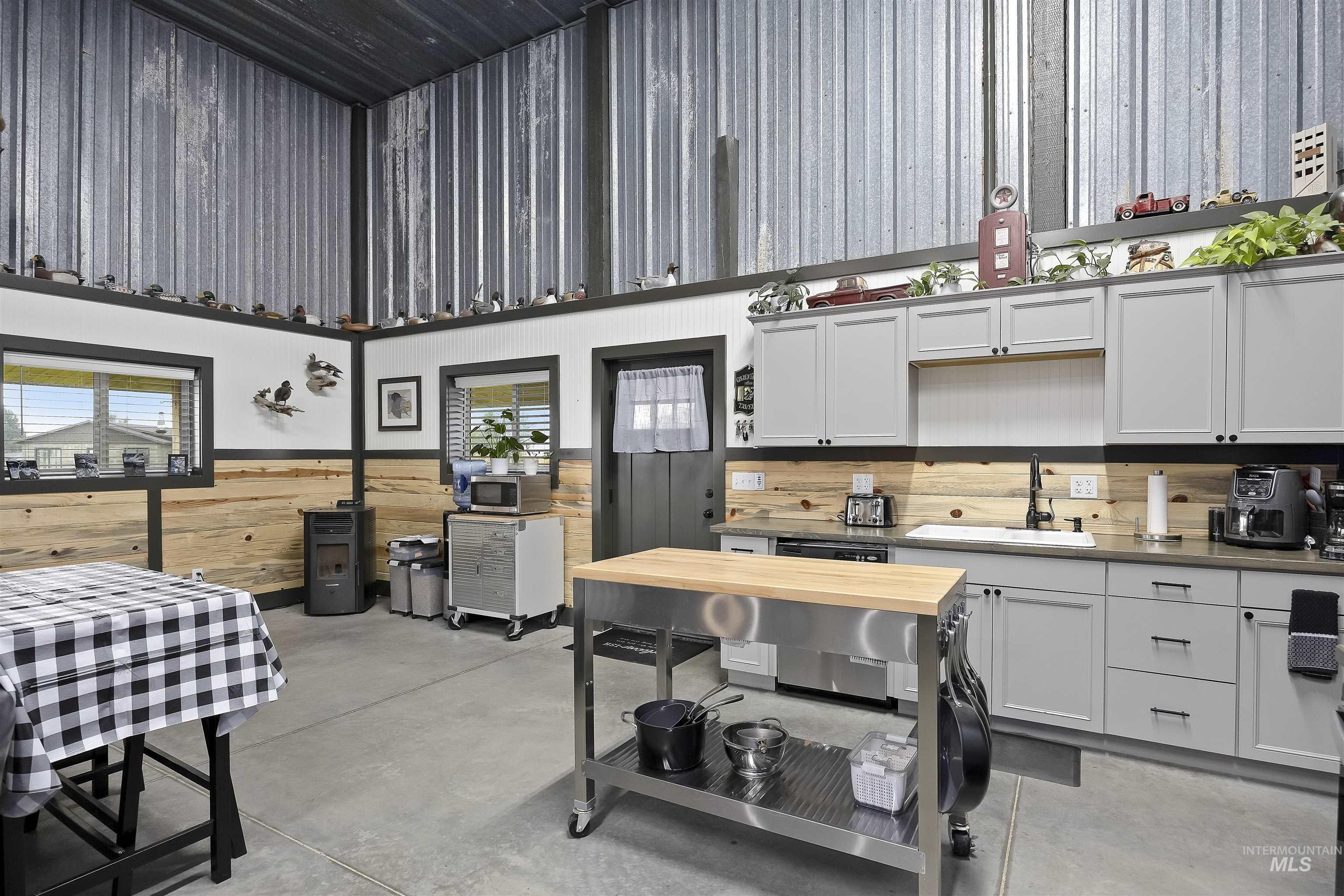 Kitchen with concrete floors, stainless steel appliances, light countertops, a towering ceiling, and wooden walls