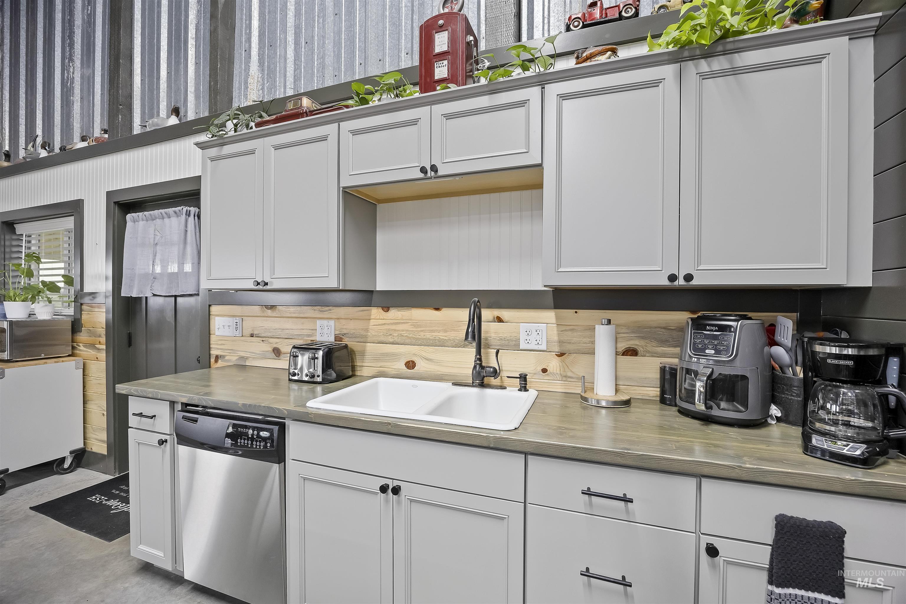 Kitchen featuring appliances with stainless steel finishes, white cabinets, light countertops, and concrete floors