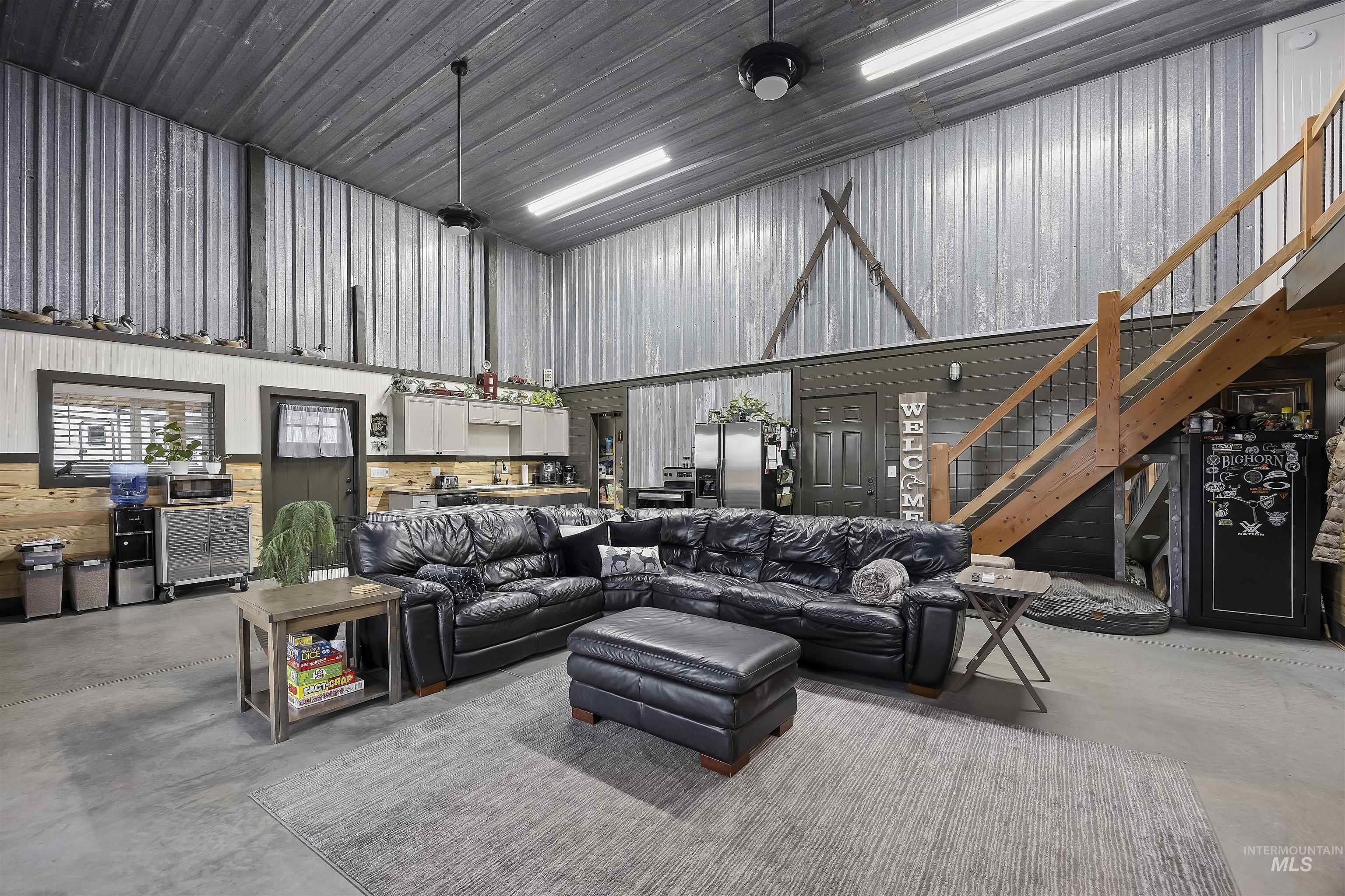Living room with finished concrete floors, metal wall, a towering ceiling, and stairs