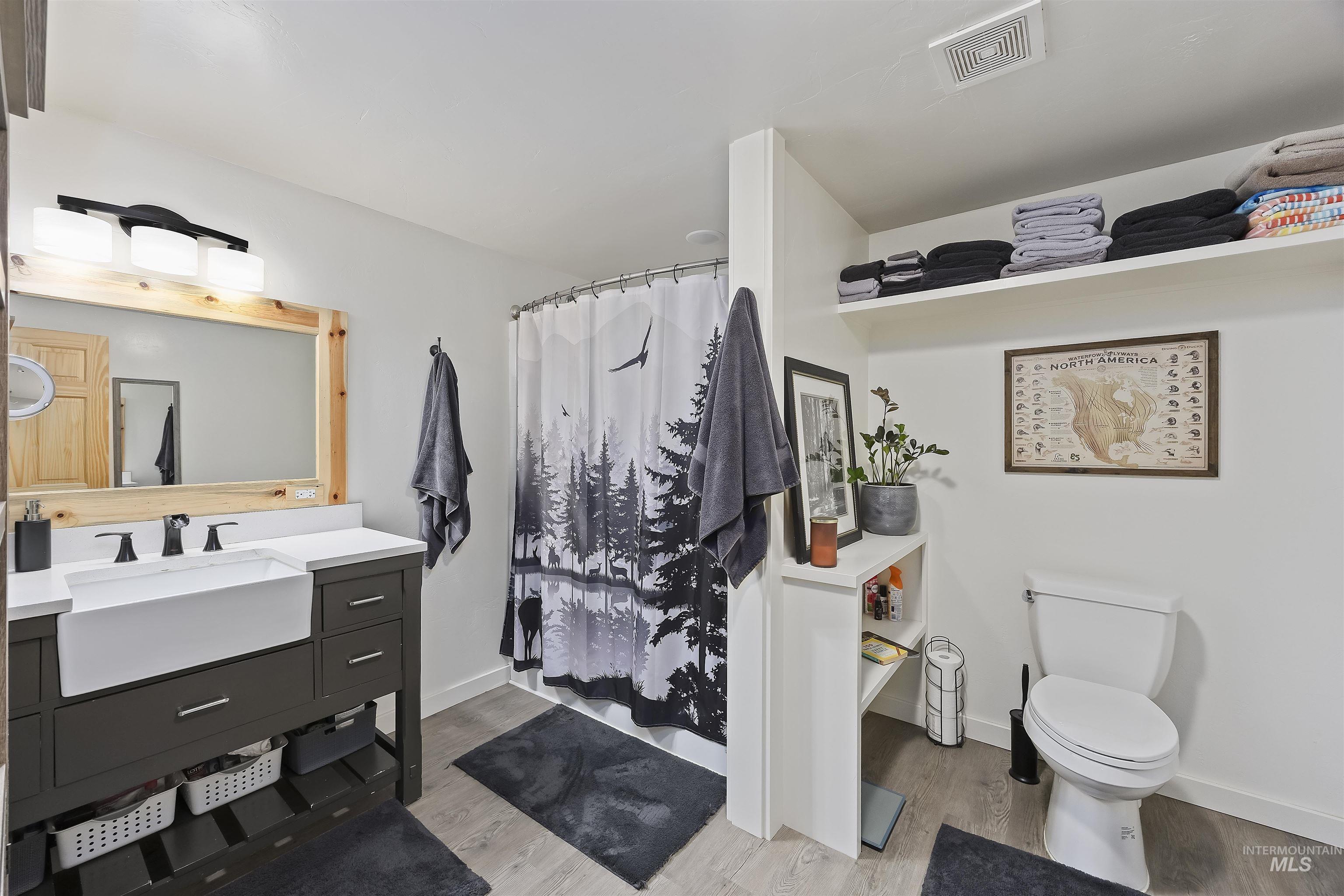 Full bathroom with vanity, light wood-type flooring, and curtained shower