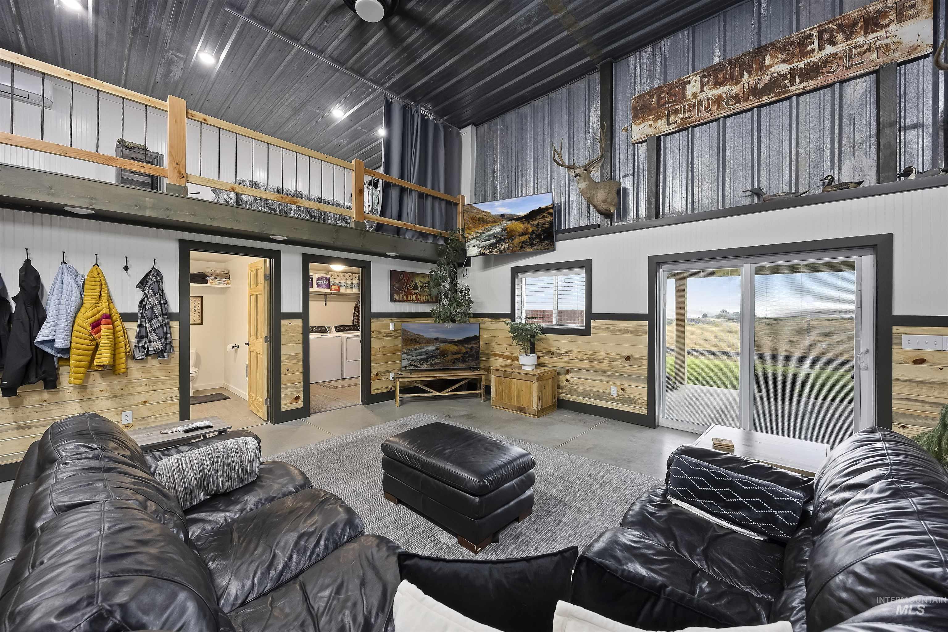 Living area with a high ceiling, concrete flooring, washer and dryer, a wainscoted wall, and wooden walls