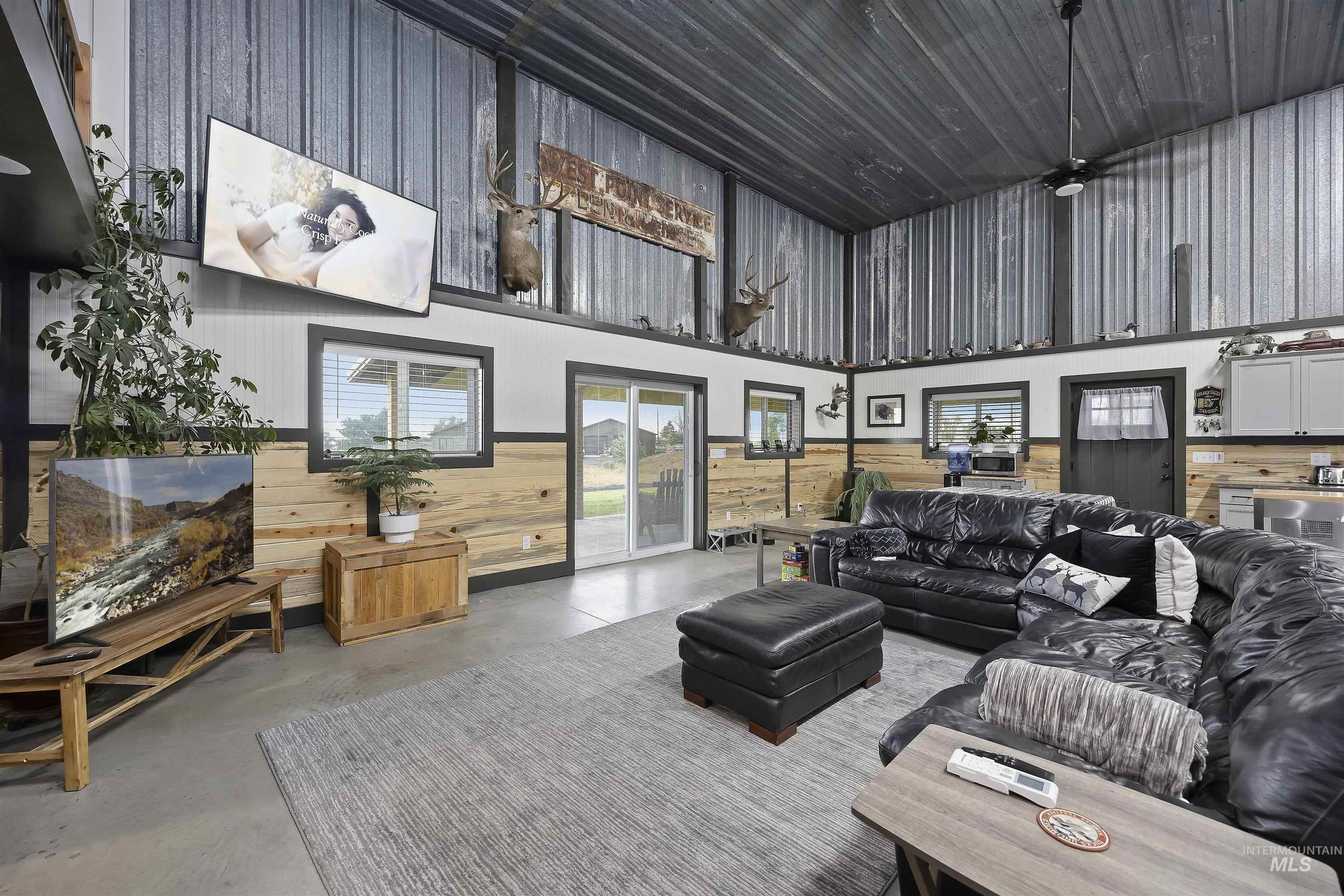Living area featuring concrete flooring, wood walls, and a towering ceiling