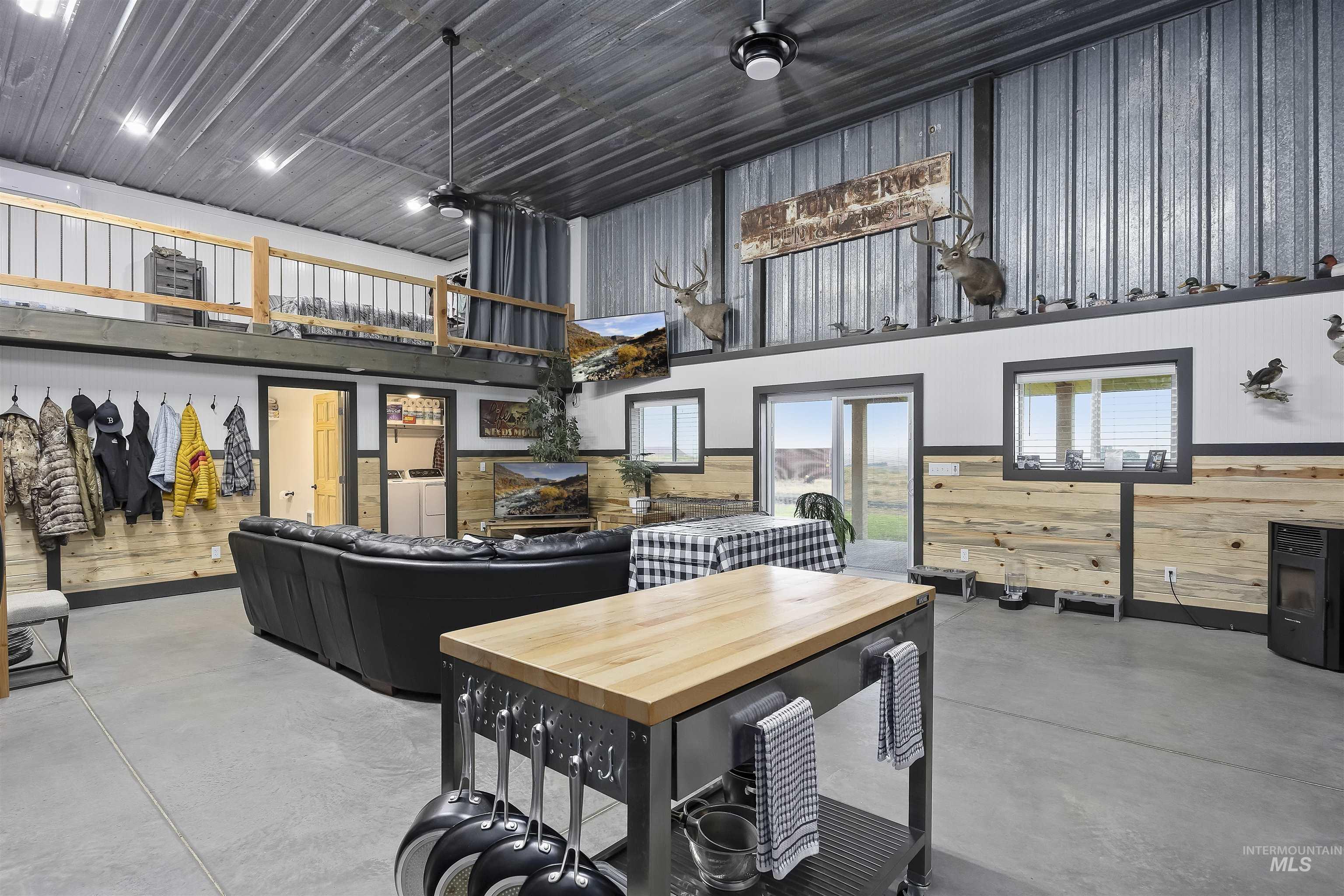 Dining space with concrete floors, wooden walls, a high ceiling, and wainscoting