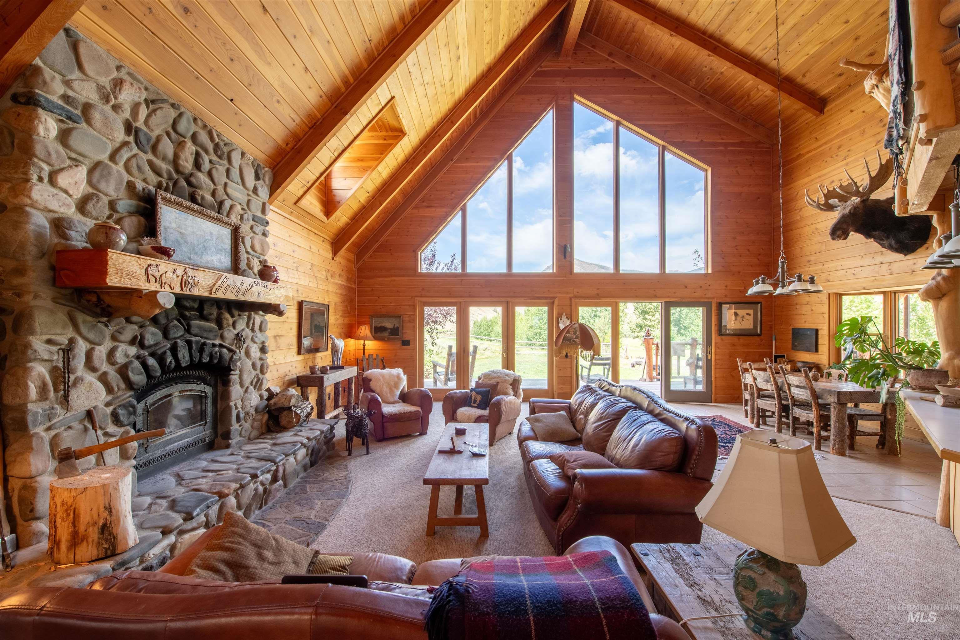 Tiled living area featuring high vaulted ceiling, wooden walls, a wood ceiling with exposed beams, a fireplace, and carpet flooring