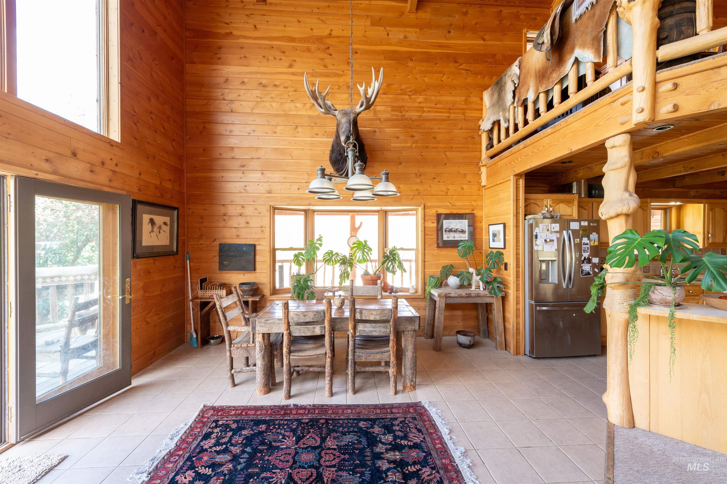 Dining area featuring light tile patterned floors, wooden walls, and a high ceiling