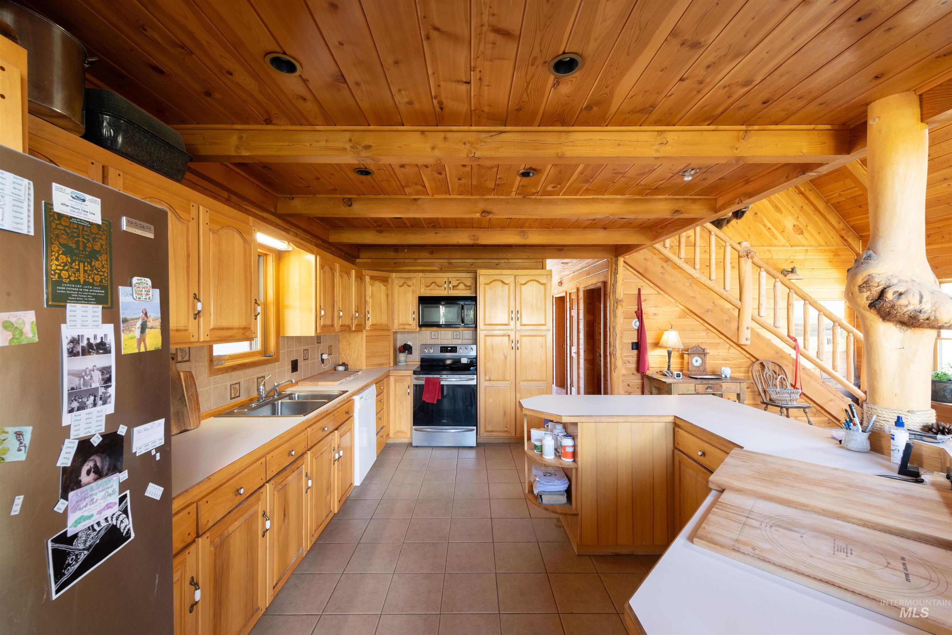 Kitchen with appliances with stainless steel finishes, open shelves, light countertops, decorative backsplash, and a wood ceiling with exposed beams