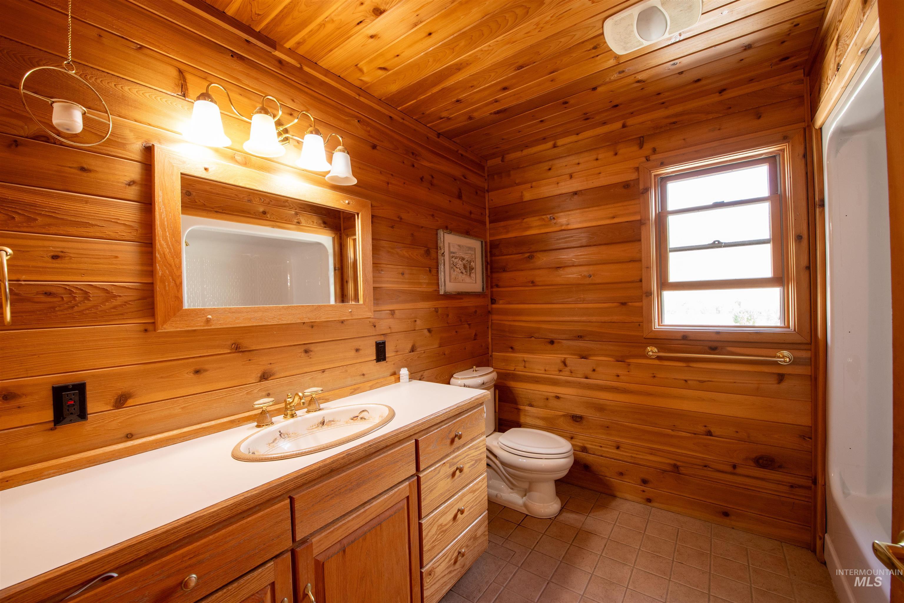 Full bathroom featuring vanity, light tile patterned floors, wood walls, and wooden ceiling