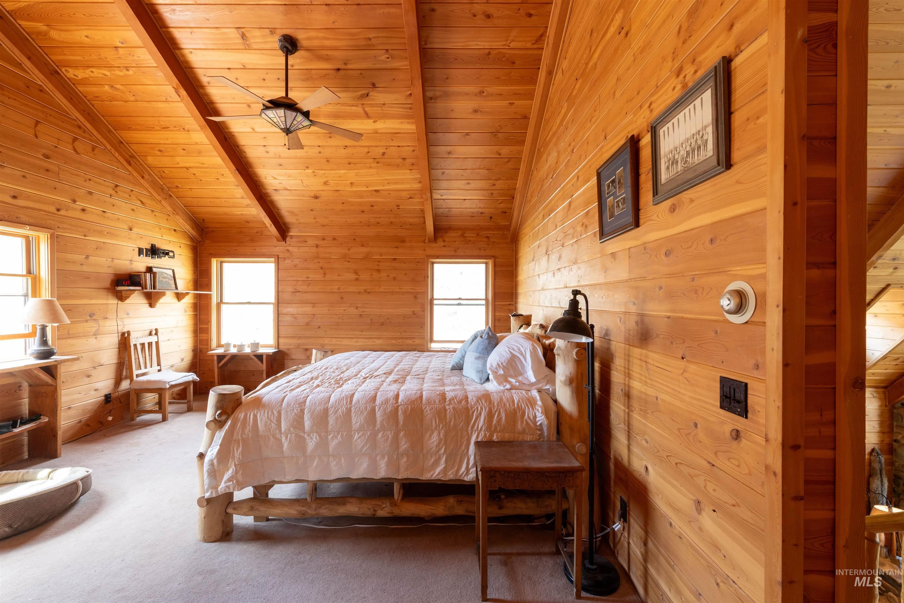 Bedroom featuring wooden ceiling, wooden walls, carpet floors, and ceiling fan