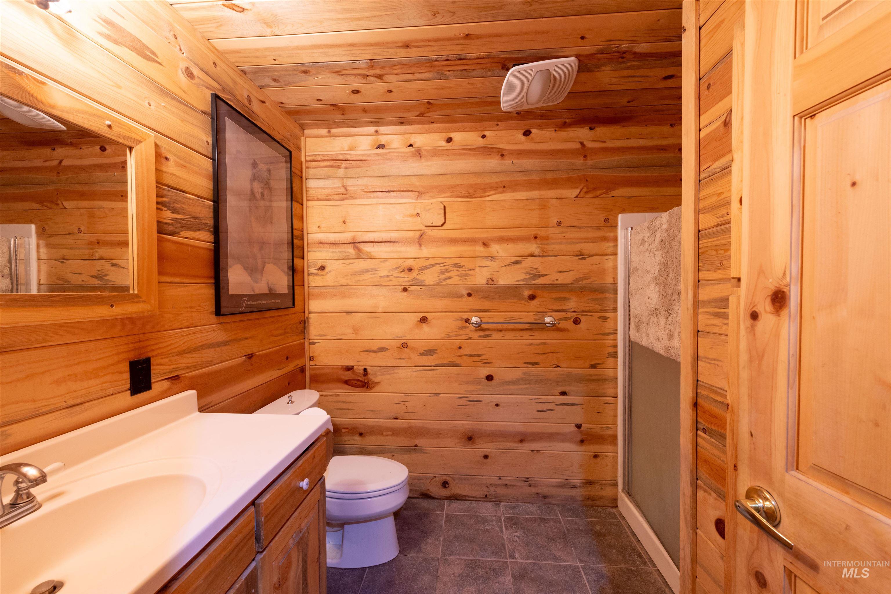 Full bath featuring vanity, wooden walls, dark tile patterned floors, and wood ceiling
