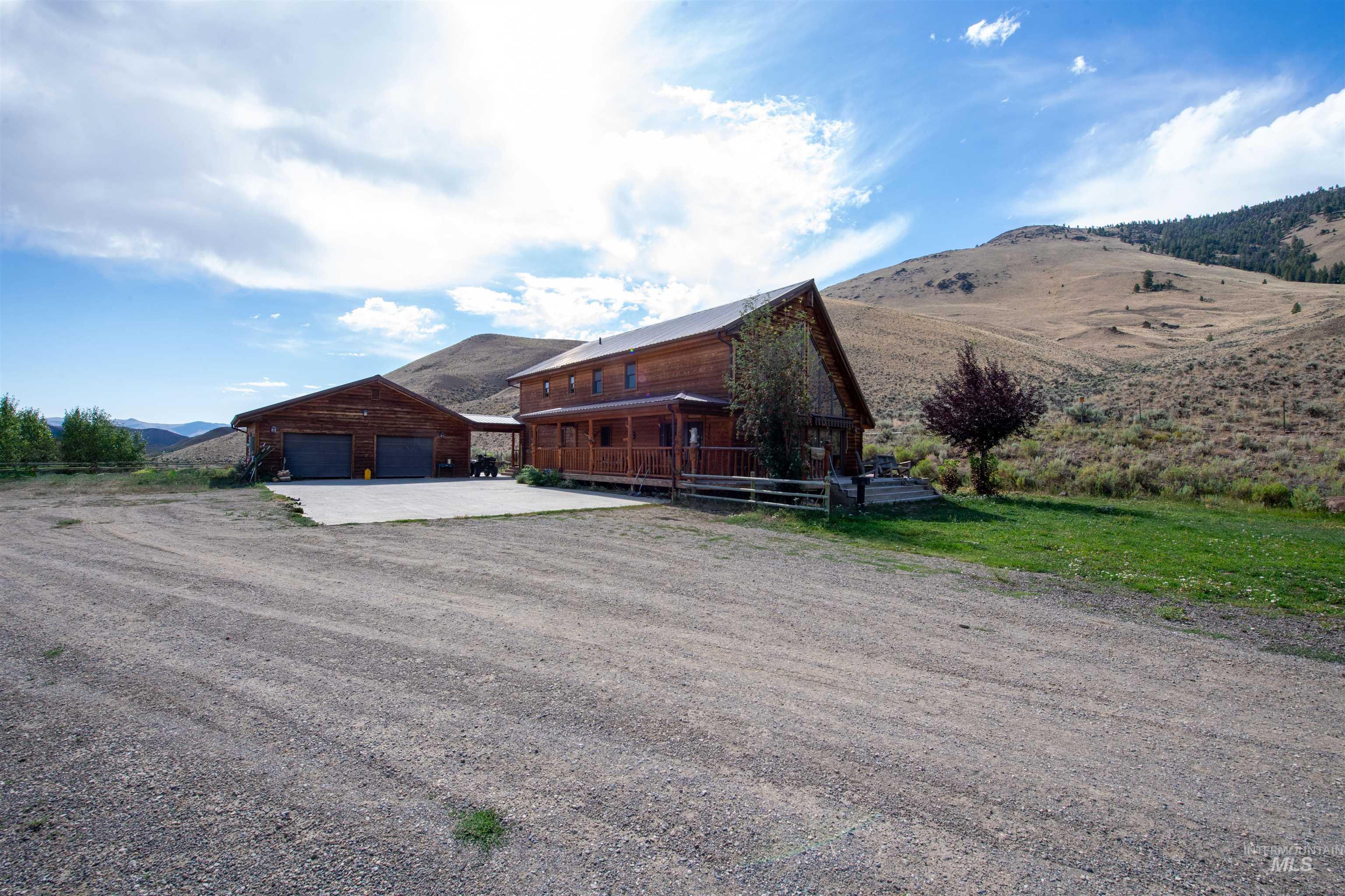 Rear view of property with driveway, a mountain view, an outbuilding, and a garage