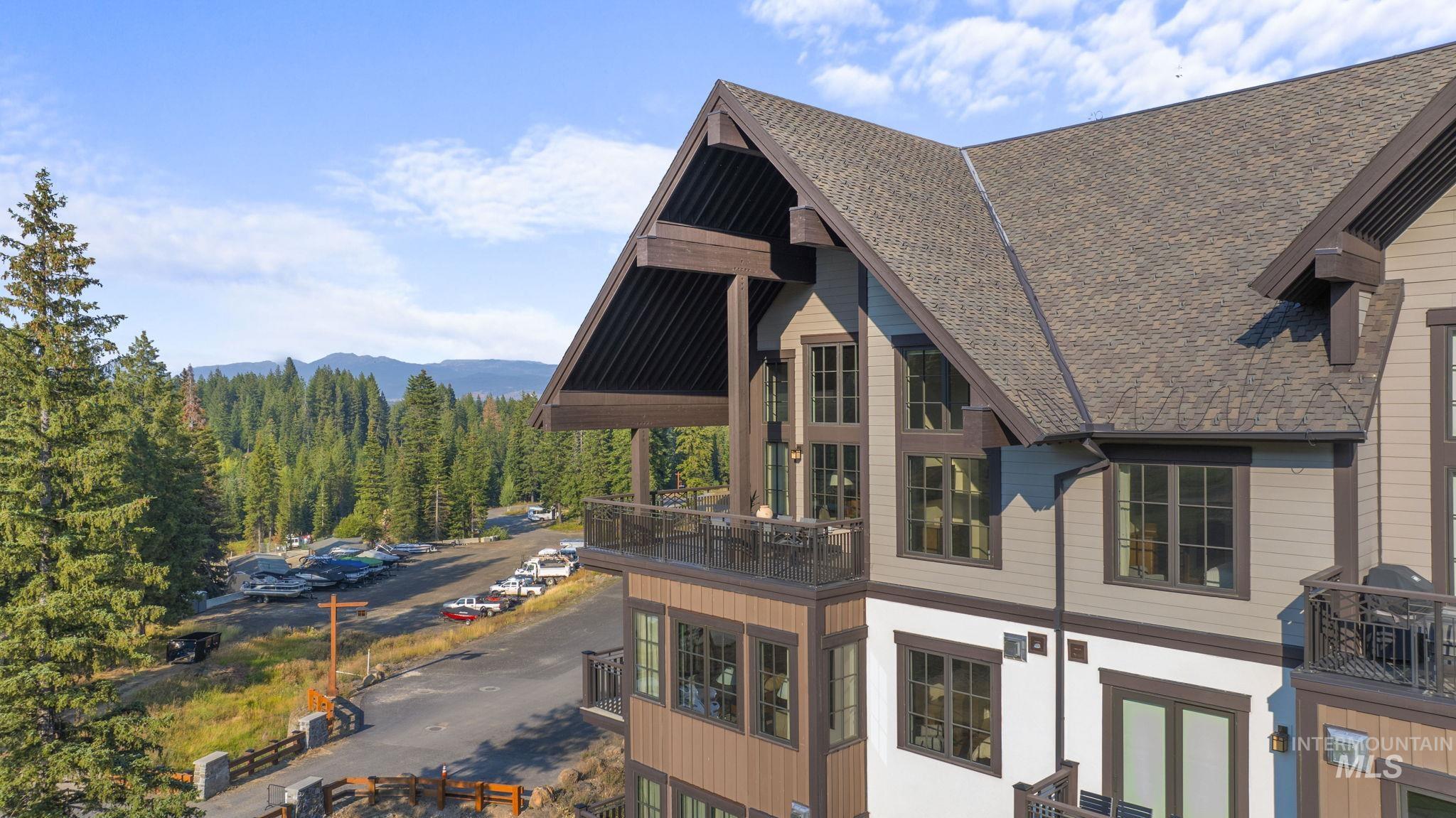 View of side of home featuring a balcony, roof with shingles, a view of trees, and a mountain view
