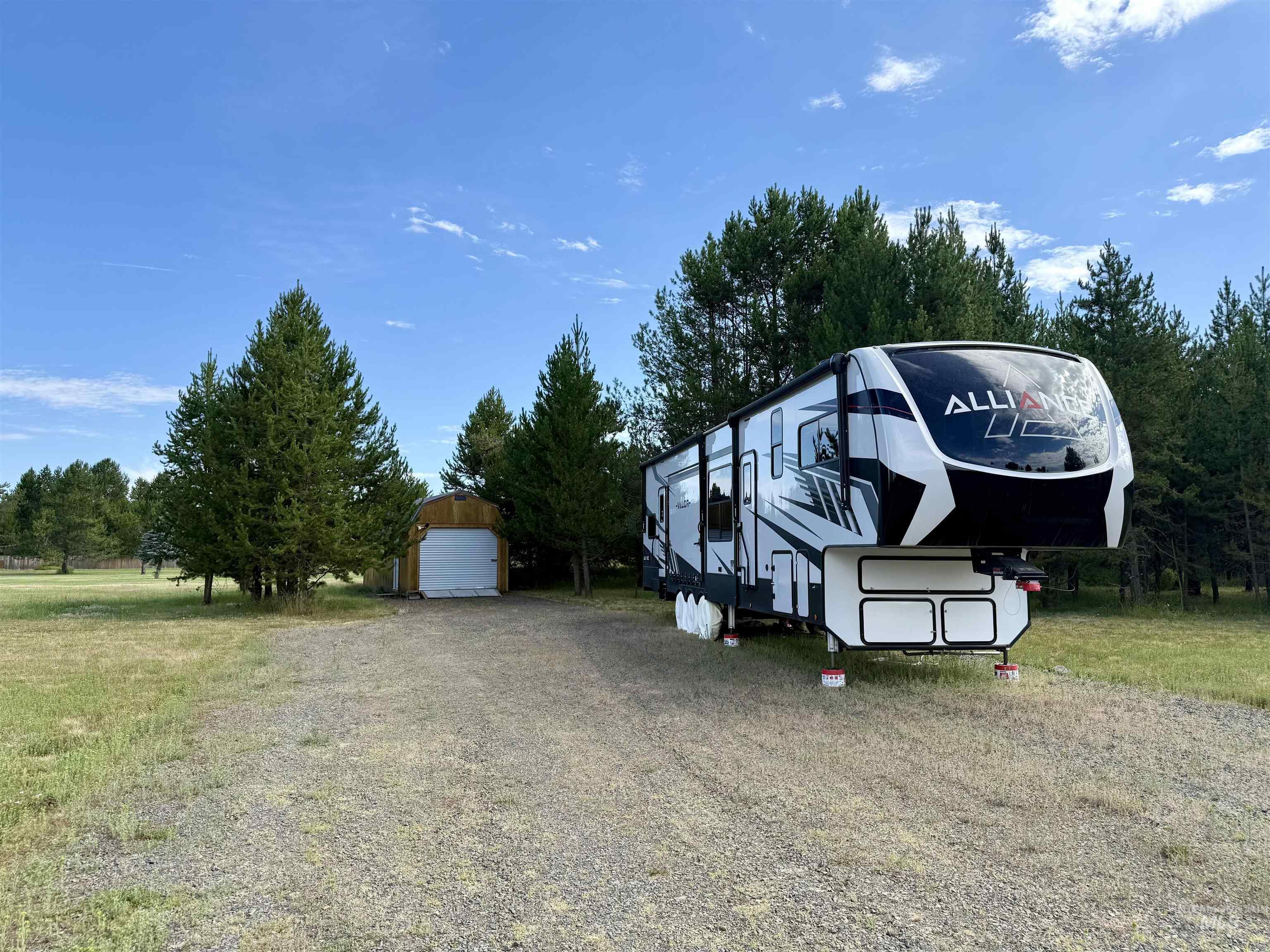 View of parking featuring a garage and gravel driveway
